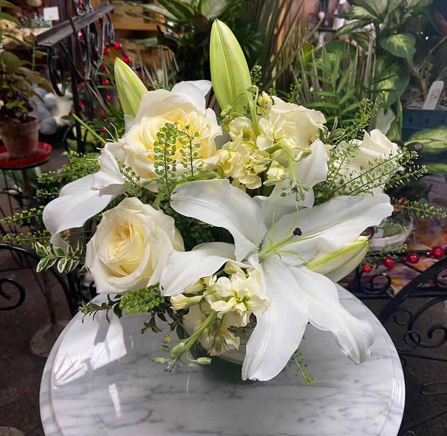 Low arrangement of white lilies and cream roses on a marble table