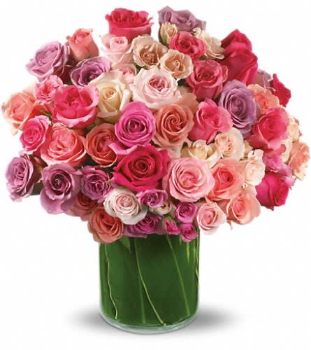 Round arrangement of pink, peach, and lavender roses in a clear glass cylinder vase