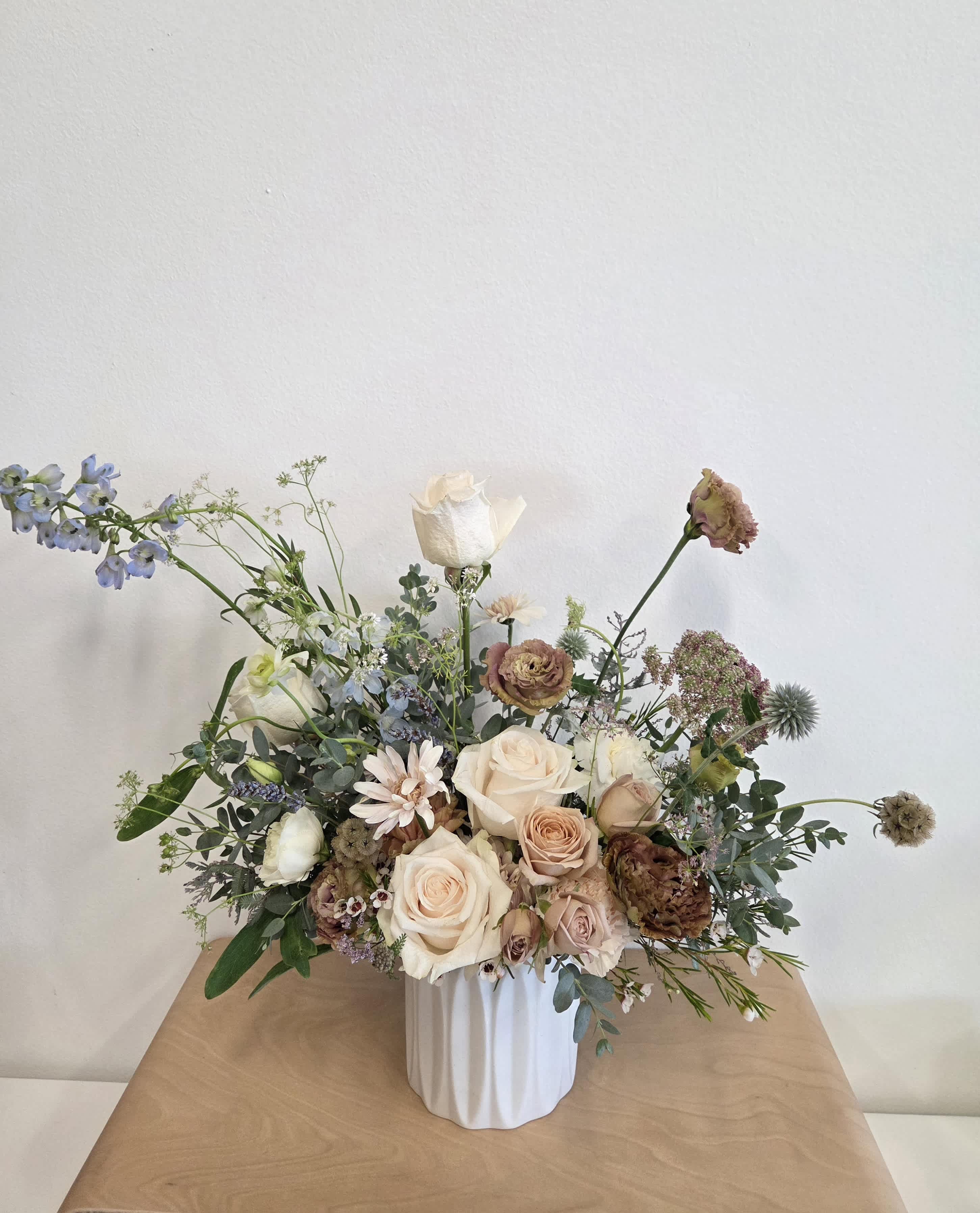 Loose bouquet of cream and blush roses in a white vase