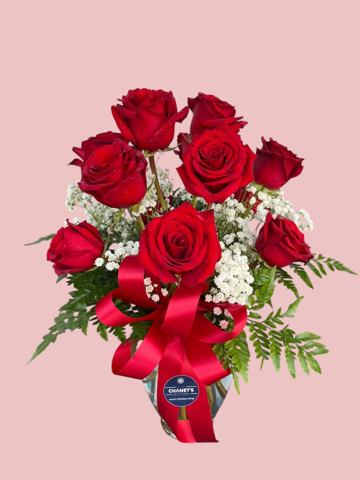Bouquet of red roses with baby's breath in a glass vase and red ribbon