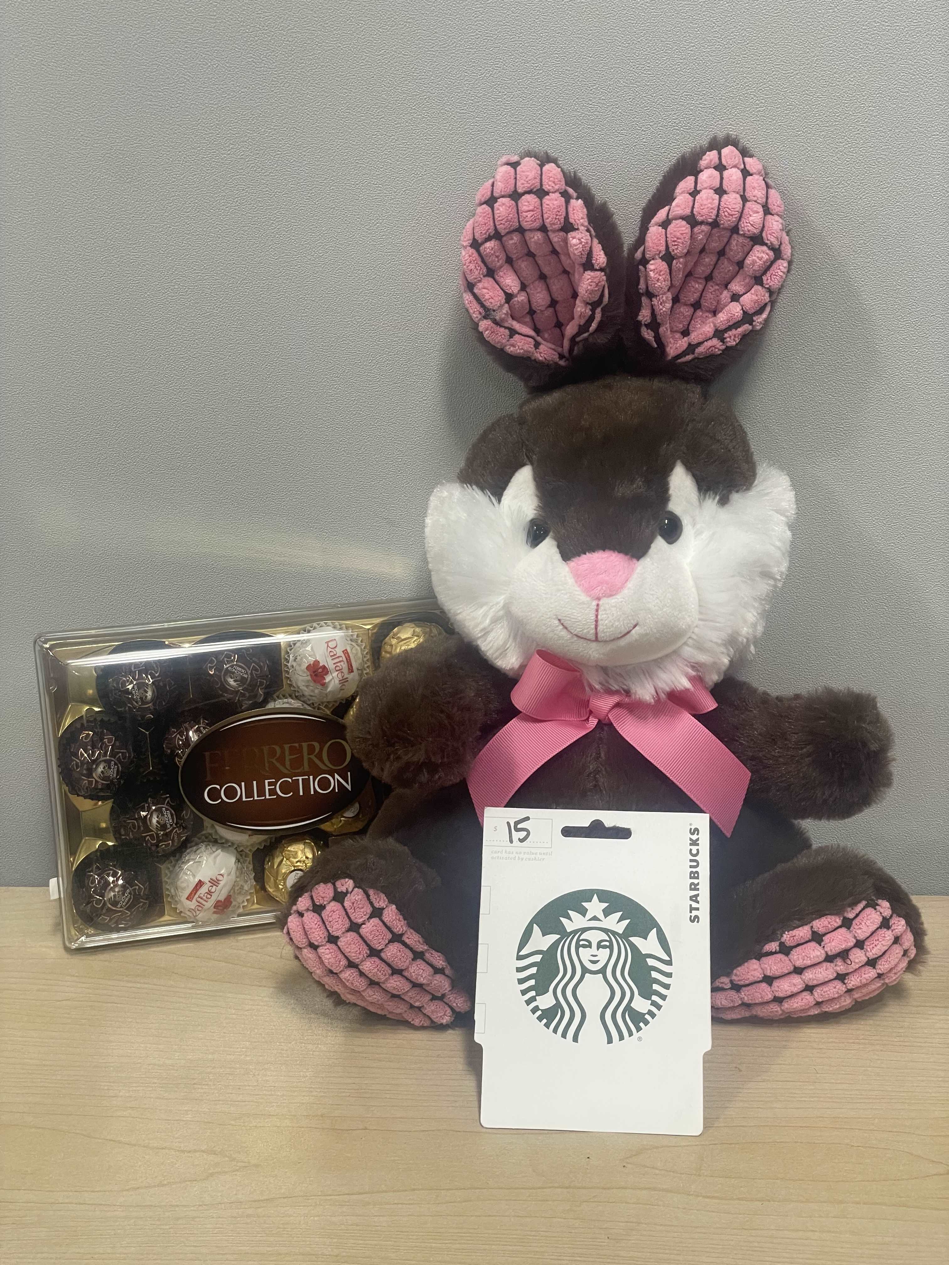 Plush bunny with a pink ribbon beside a Ferrero Rocher box and Starbucks card