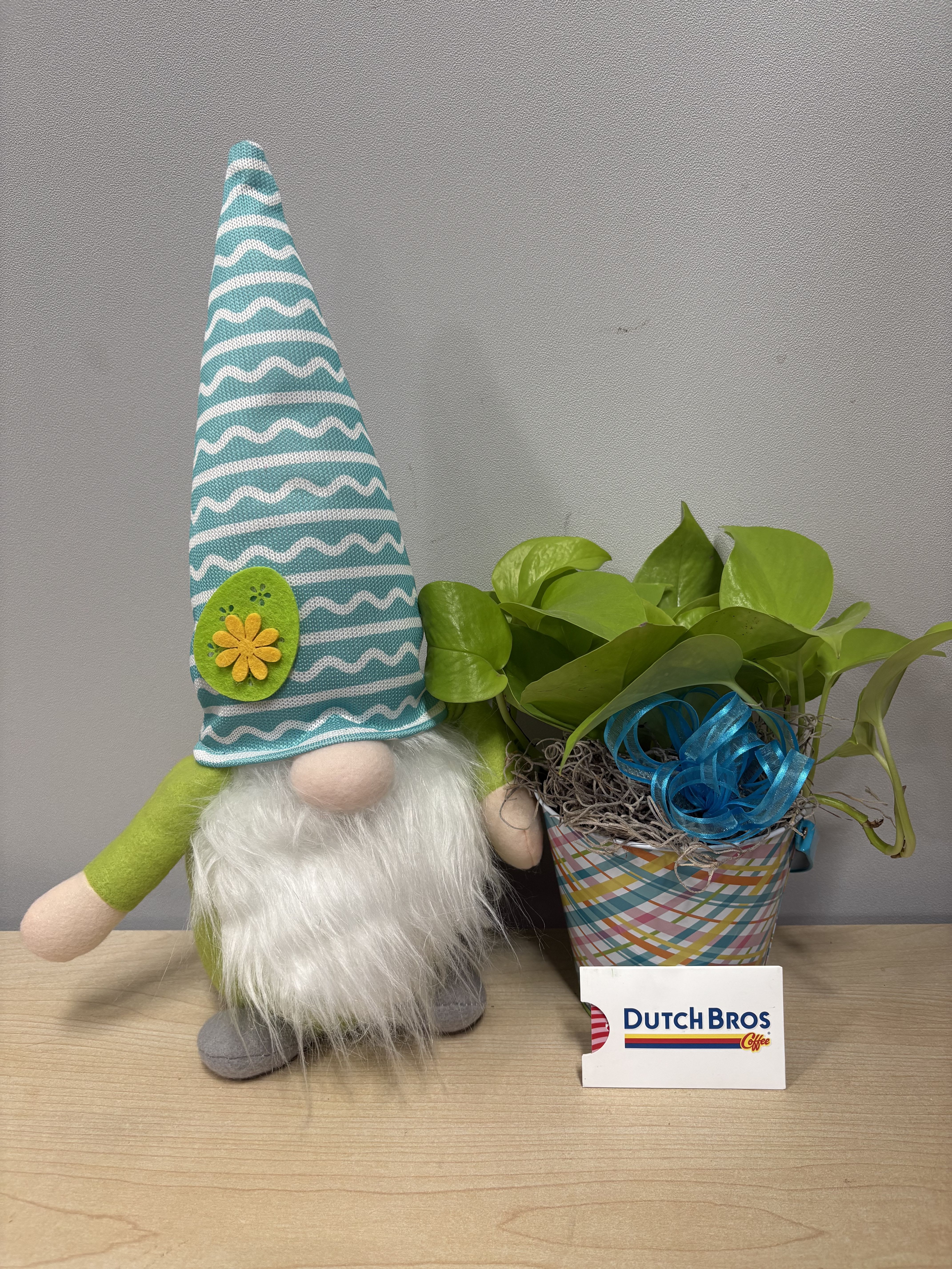 Potted green plant beside a plush gnome in a striped hat