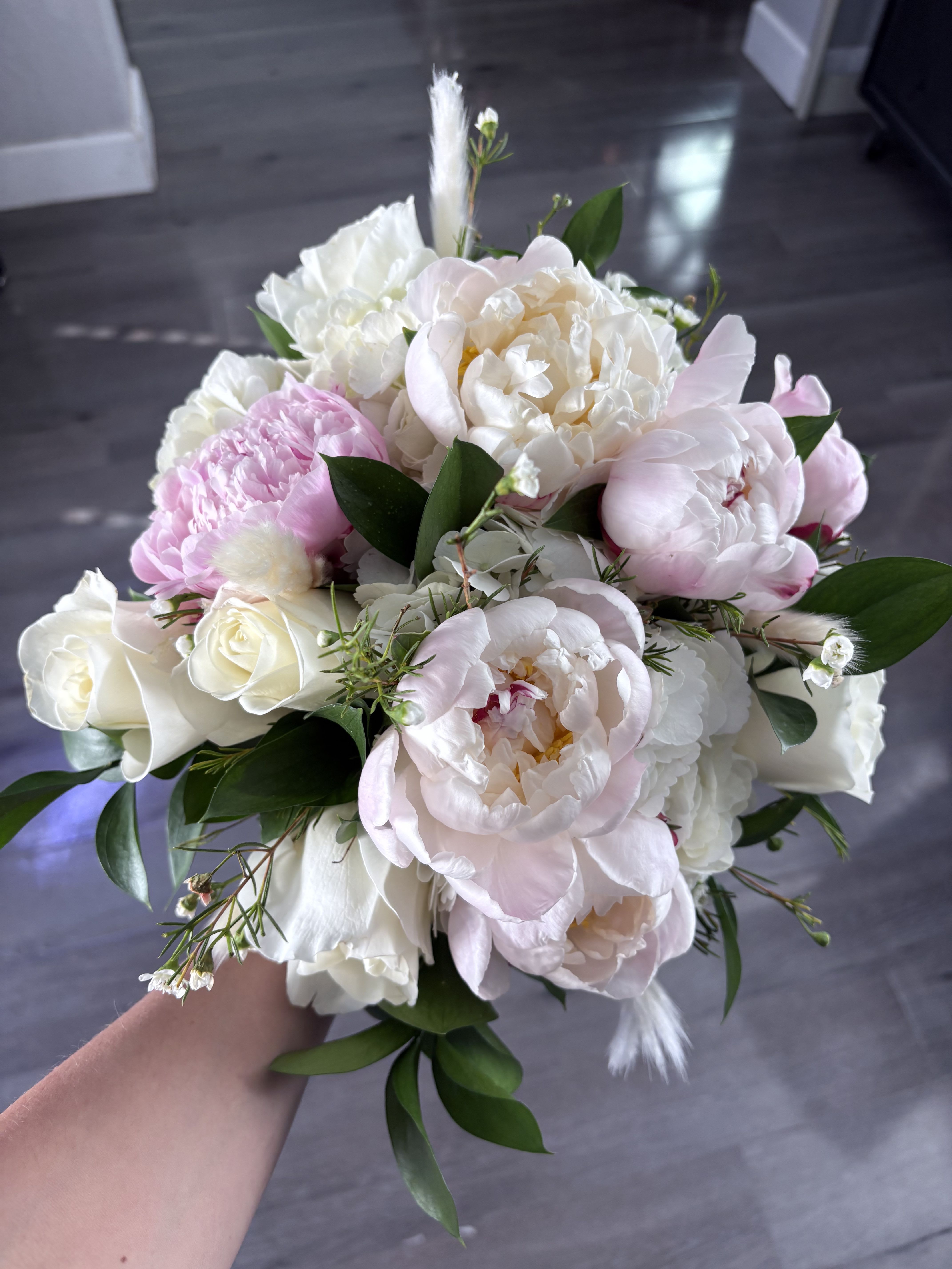 Cotton candy bouquet  - Soft blush peonies and creamy white roses come together in a compact flower arrangement that reads like cotton candy in bloom-perfect for a romantic anniversary bouquet, a Mother's Day surprise, or a gentle "thinking of you" gift. The pastel pink and white palette also makes this arrangement a lovely choice for weddings, new baby celebrations, Easter, or a delicate sympathy tribute that feels tender rather than formal.  This bouquet features large, ruffled peonies paired with smooth white roses, small white filler blooms, and rich glossy foliage for a finished, rounded silhouette that feels both lush and intimate. The mix of textures-layered peony petals against sleek rose blooms-creates visual depth and a soft, fragrant presence ideal for birthdays, graduations, housewarmings, and thank-you gestures. Sized as a compact hand-tied bouquet, it's easy to display in a simple vase; to prolong bloom life, recut stems and change the water every few days.