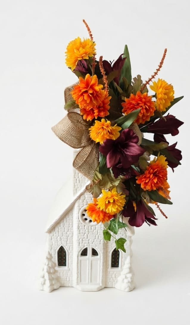 Orange and burgundy floral arrangement in a white decorative house container