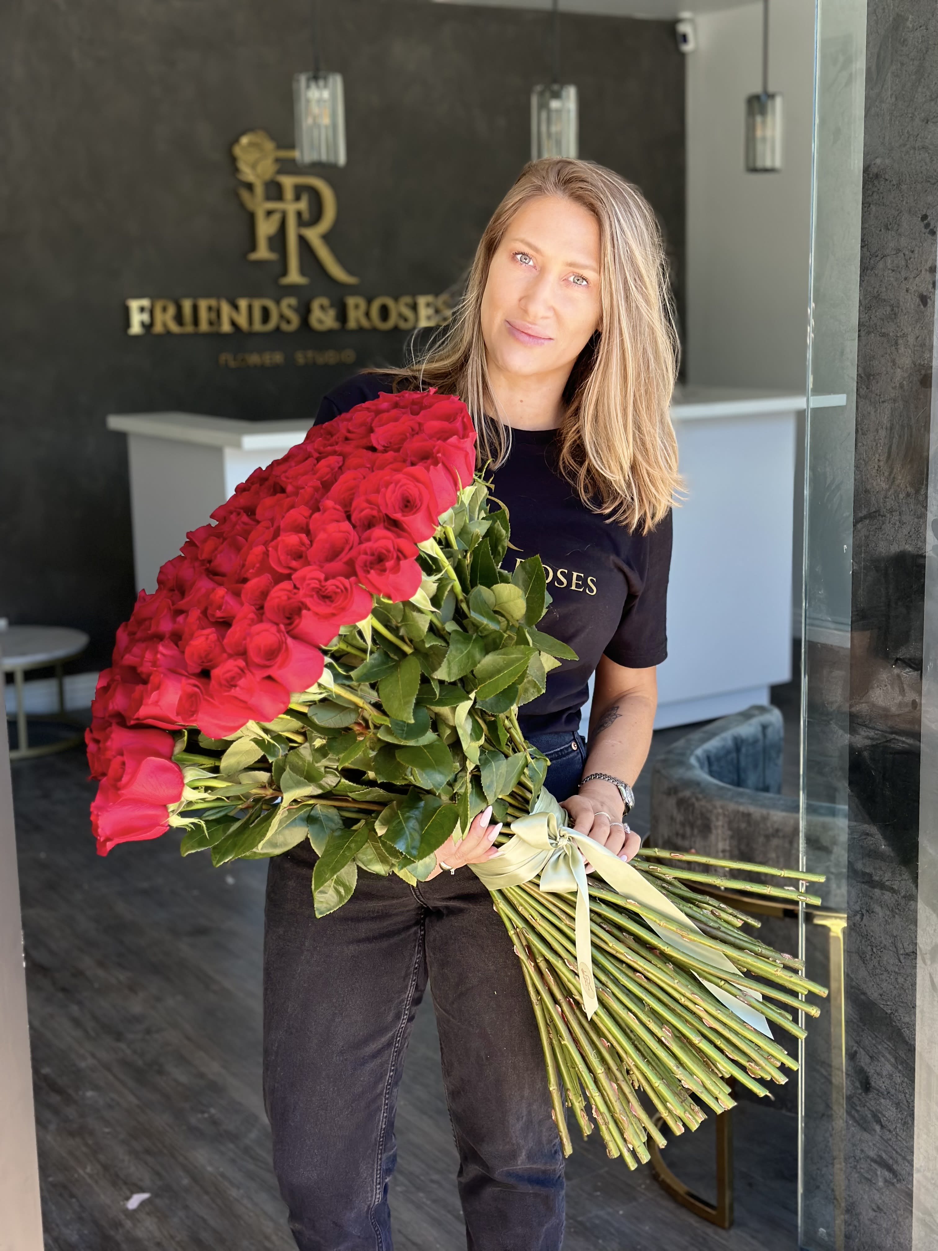 Woman holding a large bouquet of red roses tied with a ribbon
