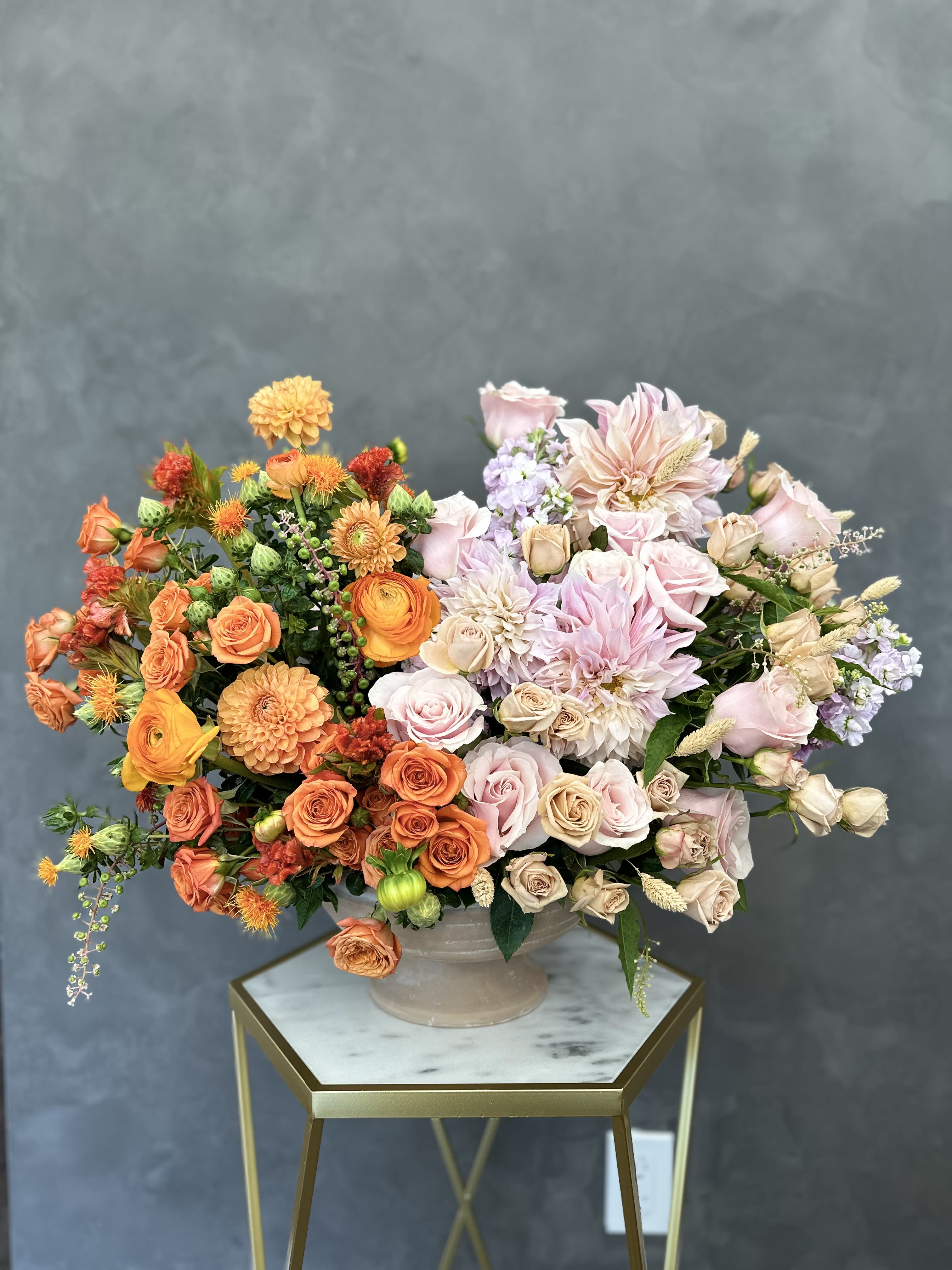 Mixed bouquet of orange, pink, and cream flowers in a ceramic vase