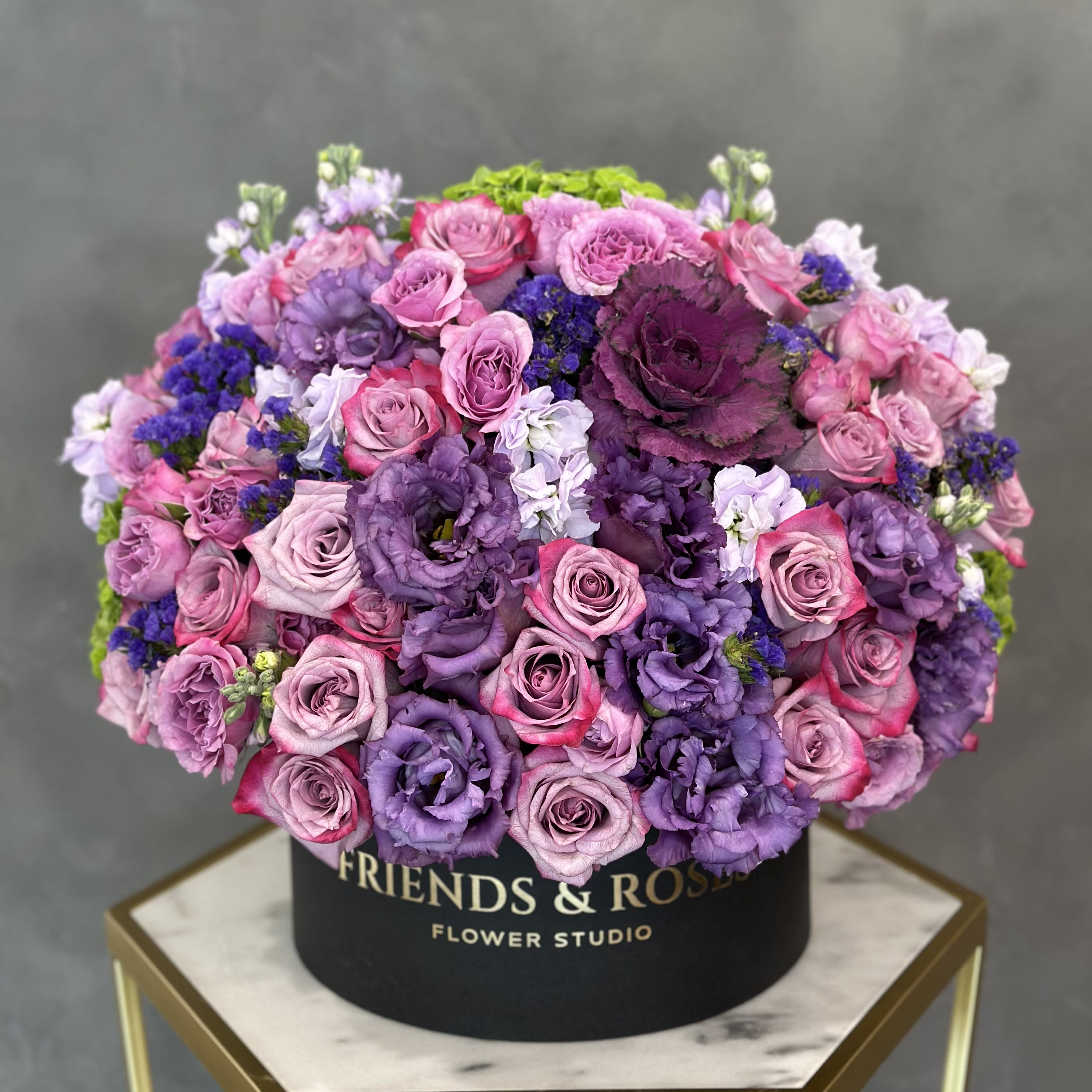 Round box arrangement of pink and purple roses and lisianthus