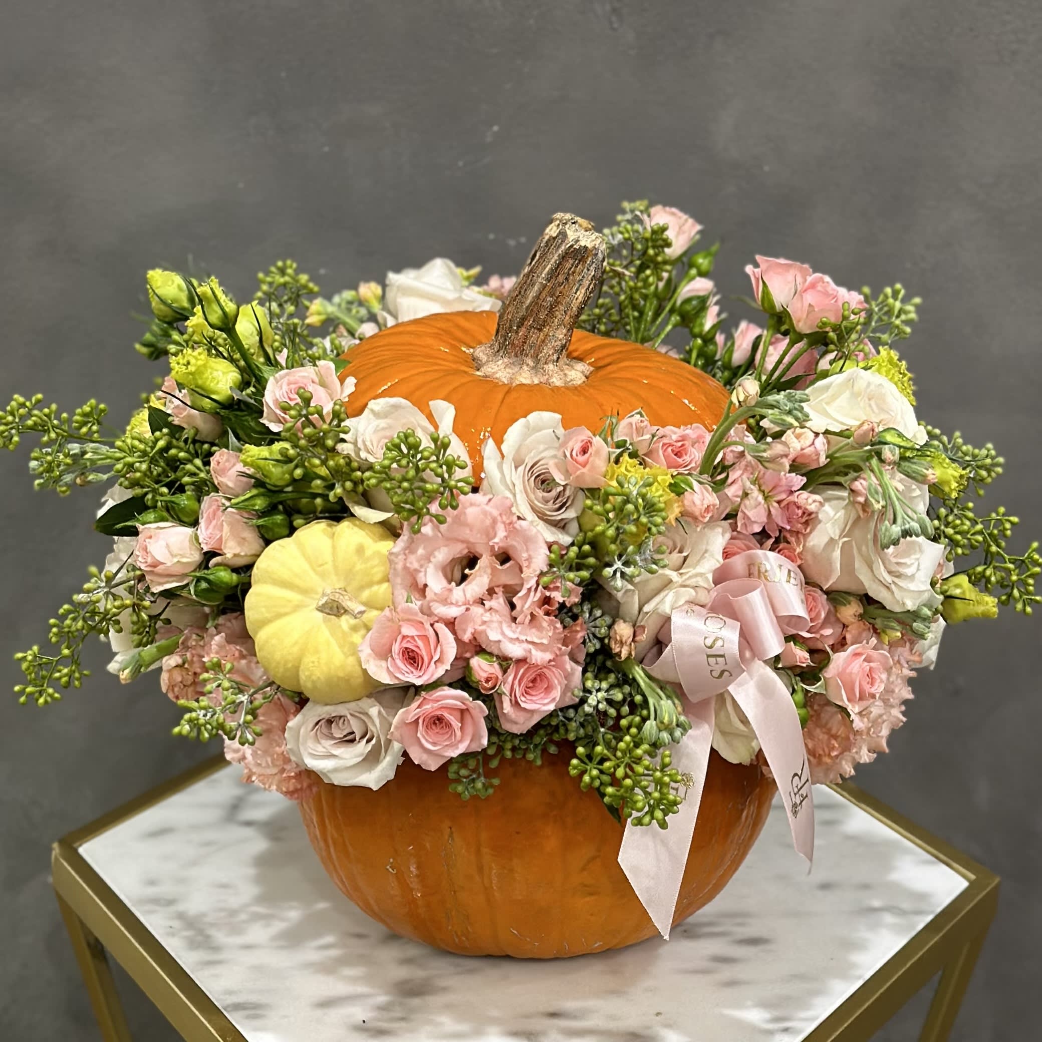 Floral arrangement in a pumpkin with pink and white blooms