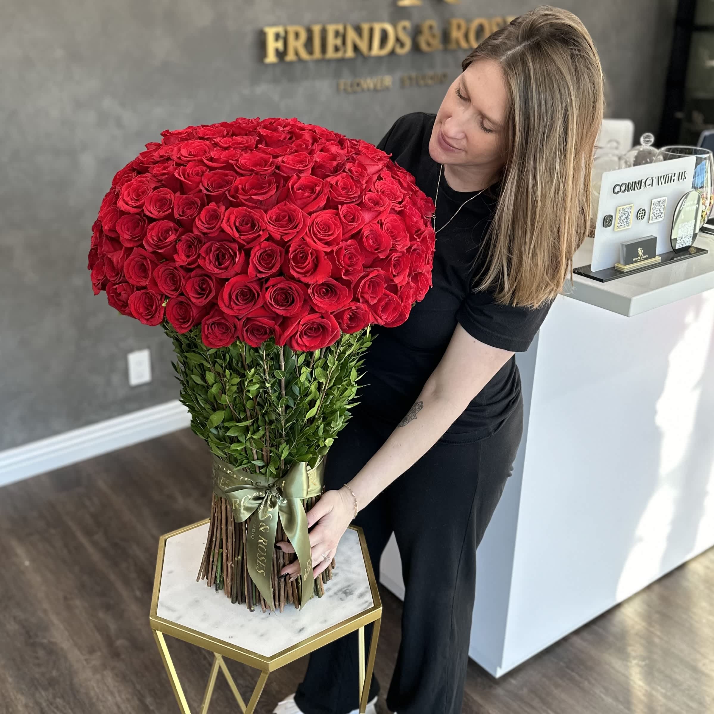 Large bouquet of red roses with a green ribbon, held by a woman