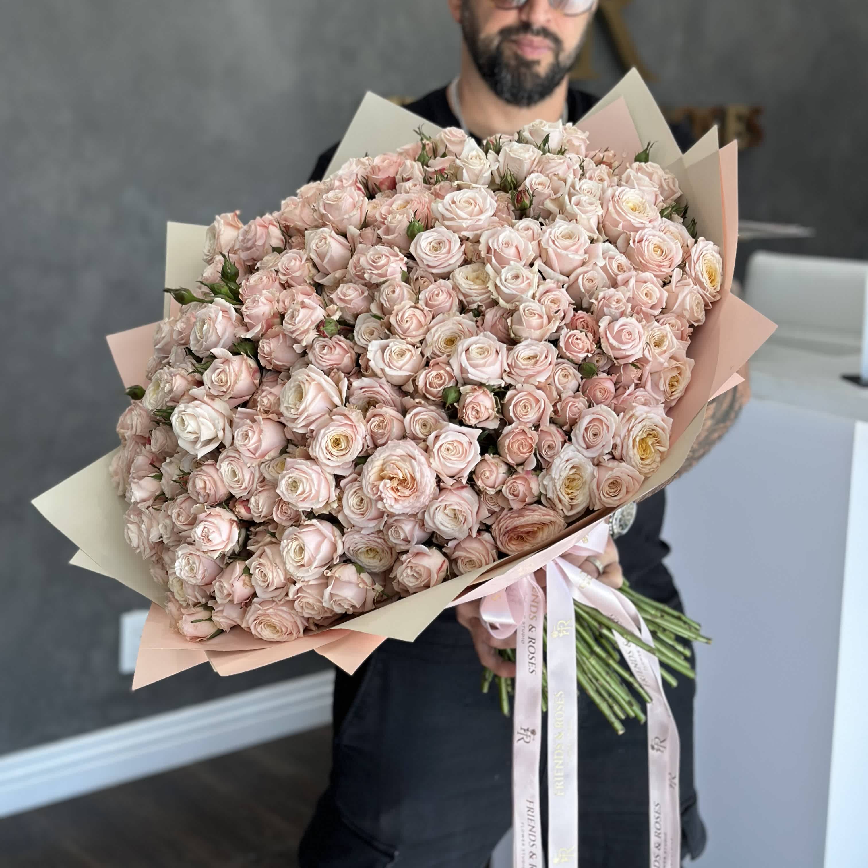 Large bouquet of pale pink spray roses wrapped in blush paper
