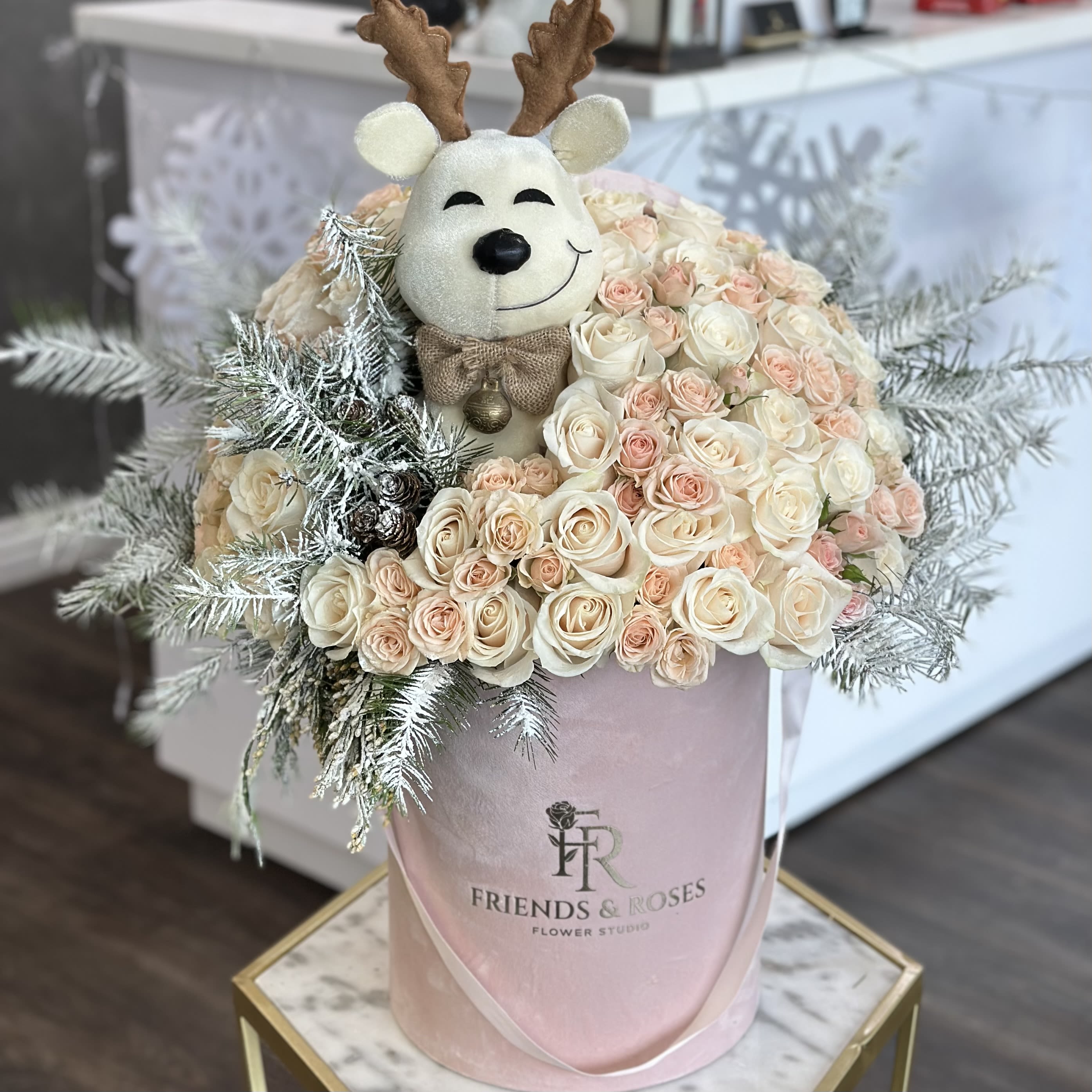 Cream and blush roses with a plush reindeer topper in a pink hatbox