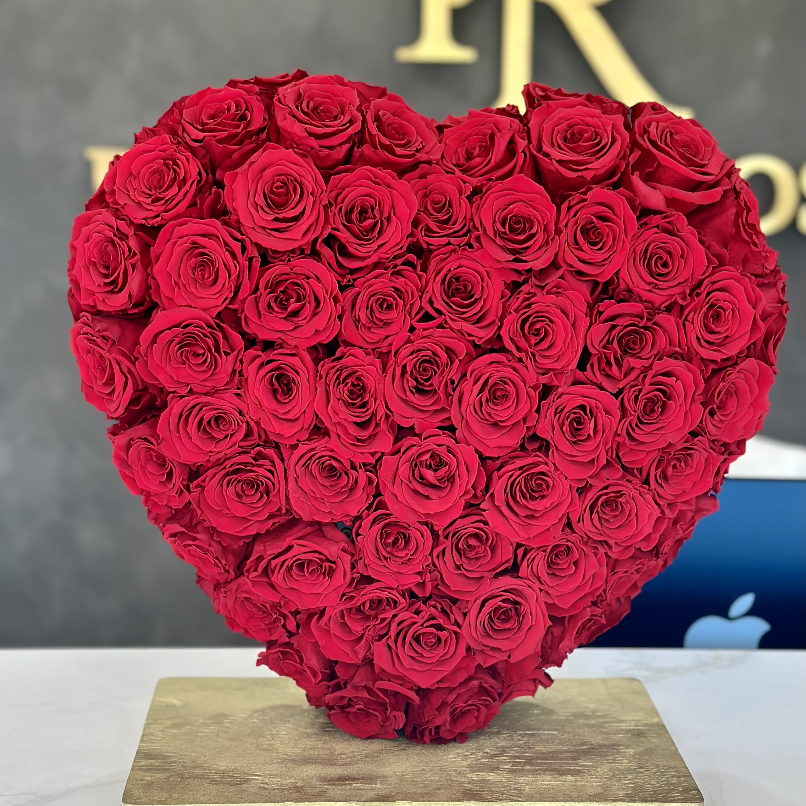 Heart-shaped arrangement of red roses on a gold base