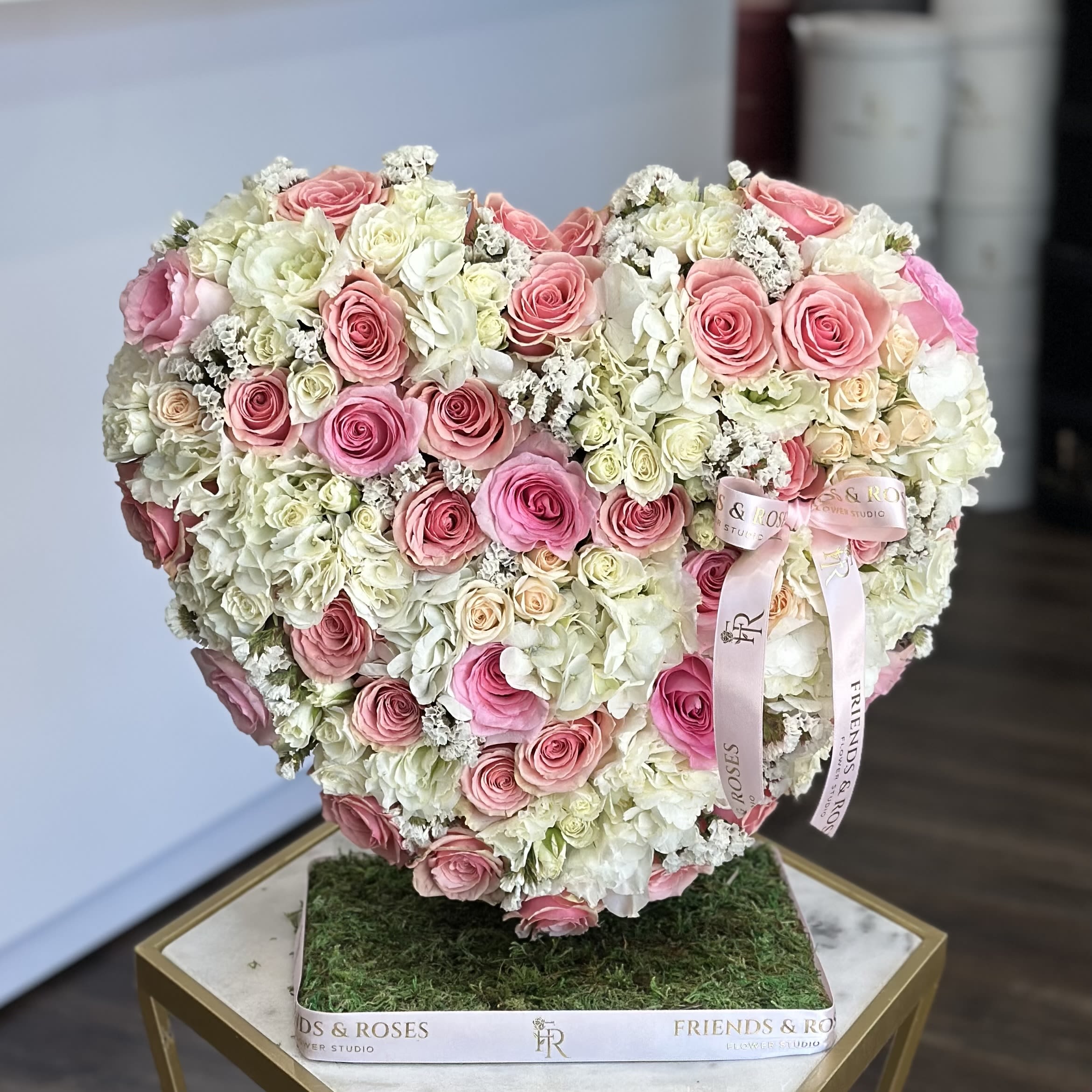 Heart-shaped arrangement of pink and white roses on a square base