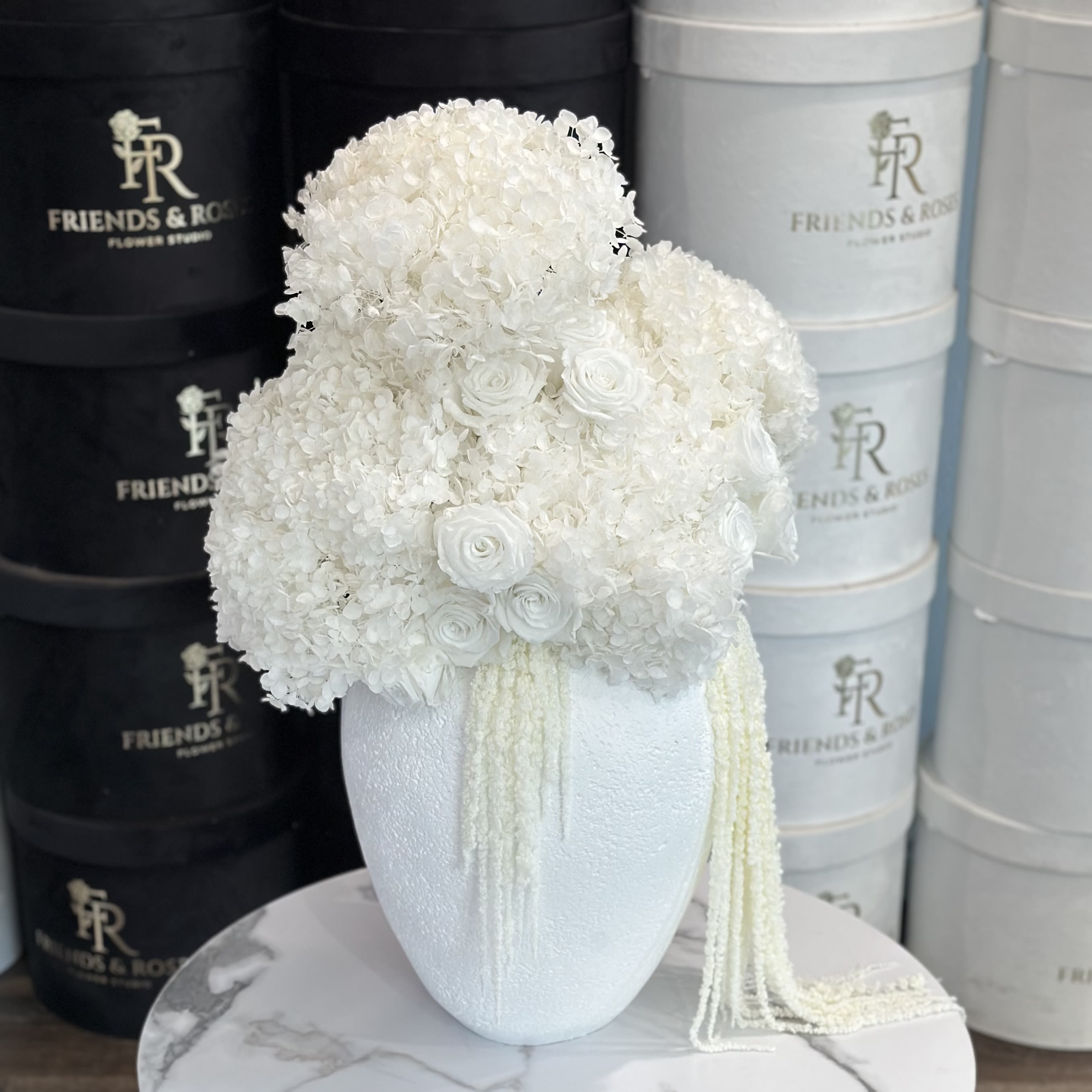 White floral arrangement in a textured vase with trailing strands