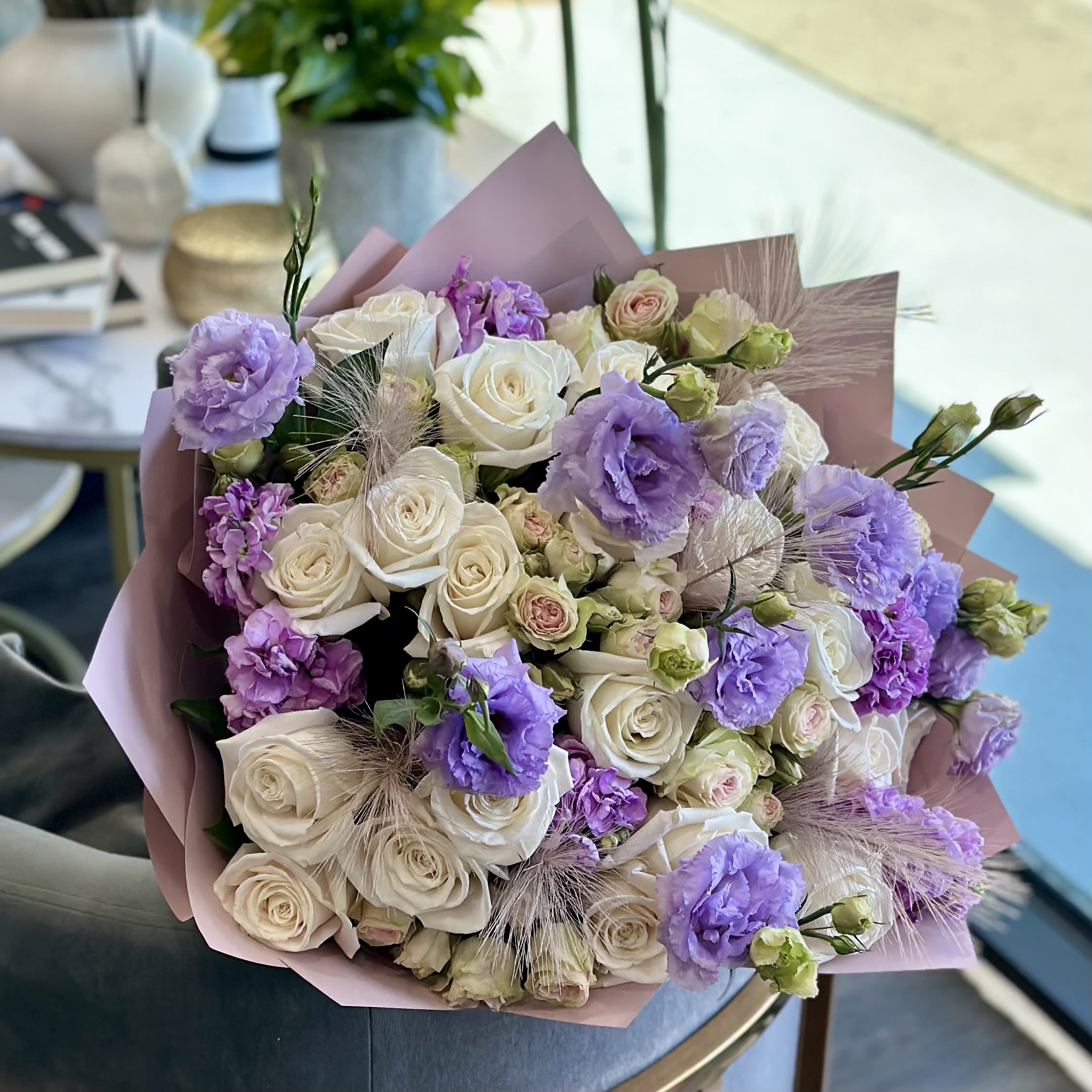 Bouquet of white roses and lavender flowers wrapped in pink paper