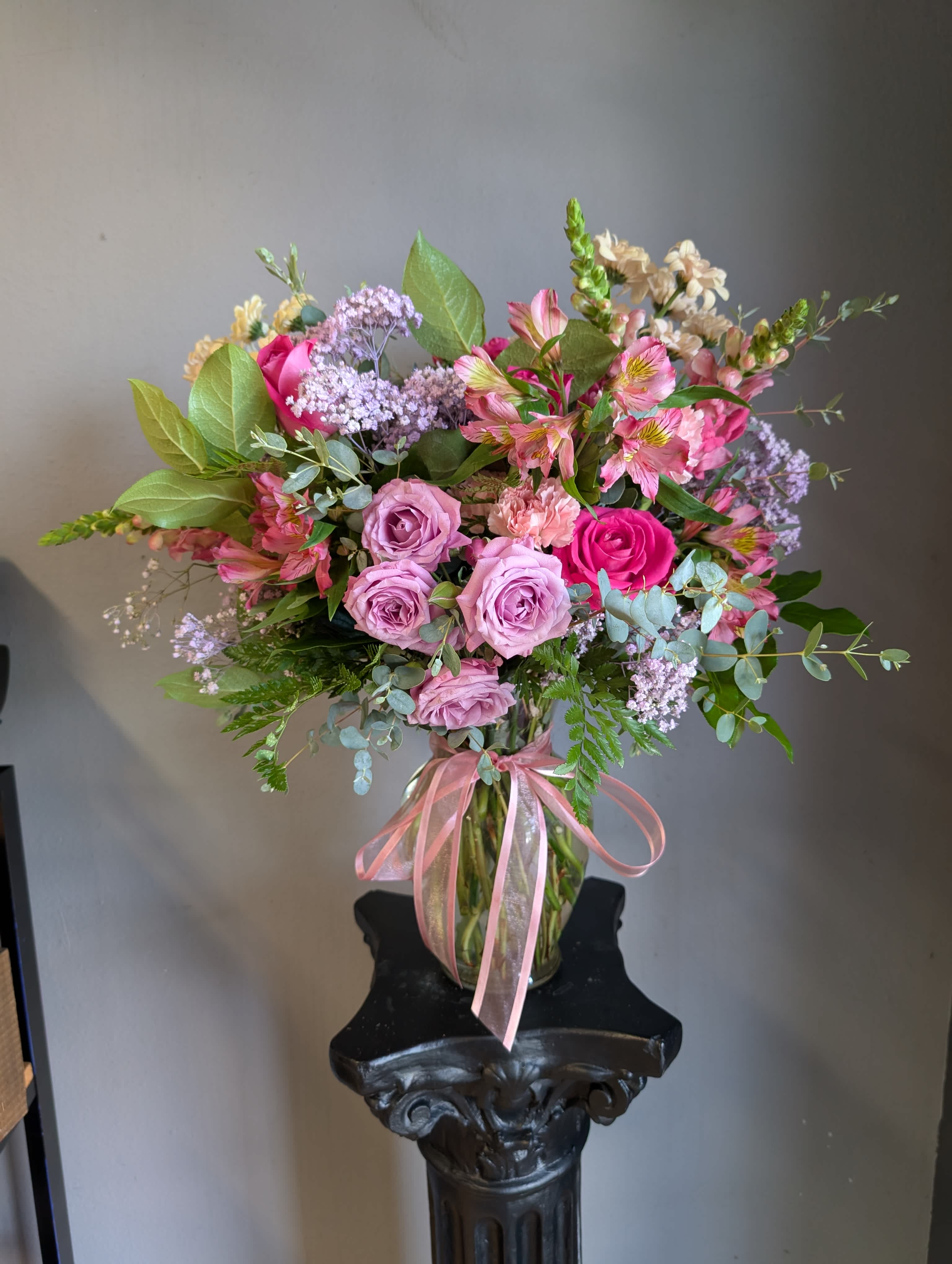 Pink and lavender bouquet in a glass vase with a pink ribbon