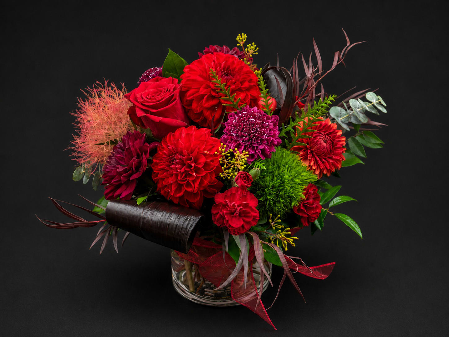 Red and magenta mixed flower arrangement in a clear glass vase