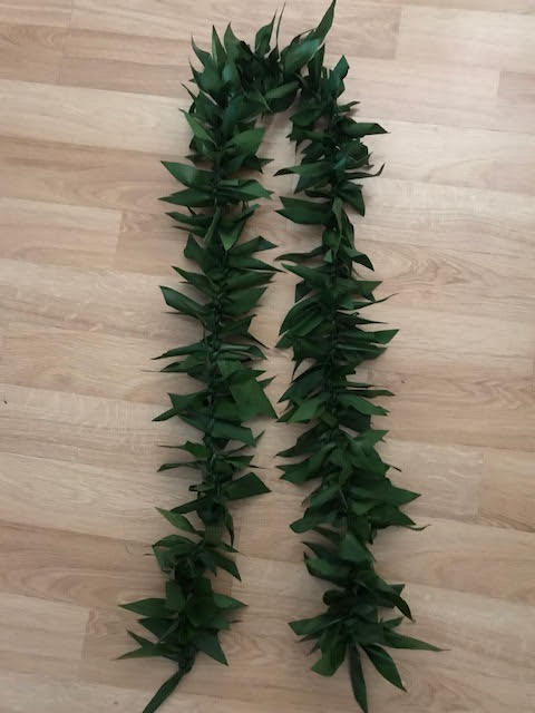 Two dark green leaf garlands laid on a wooden floor