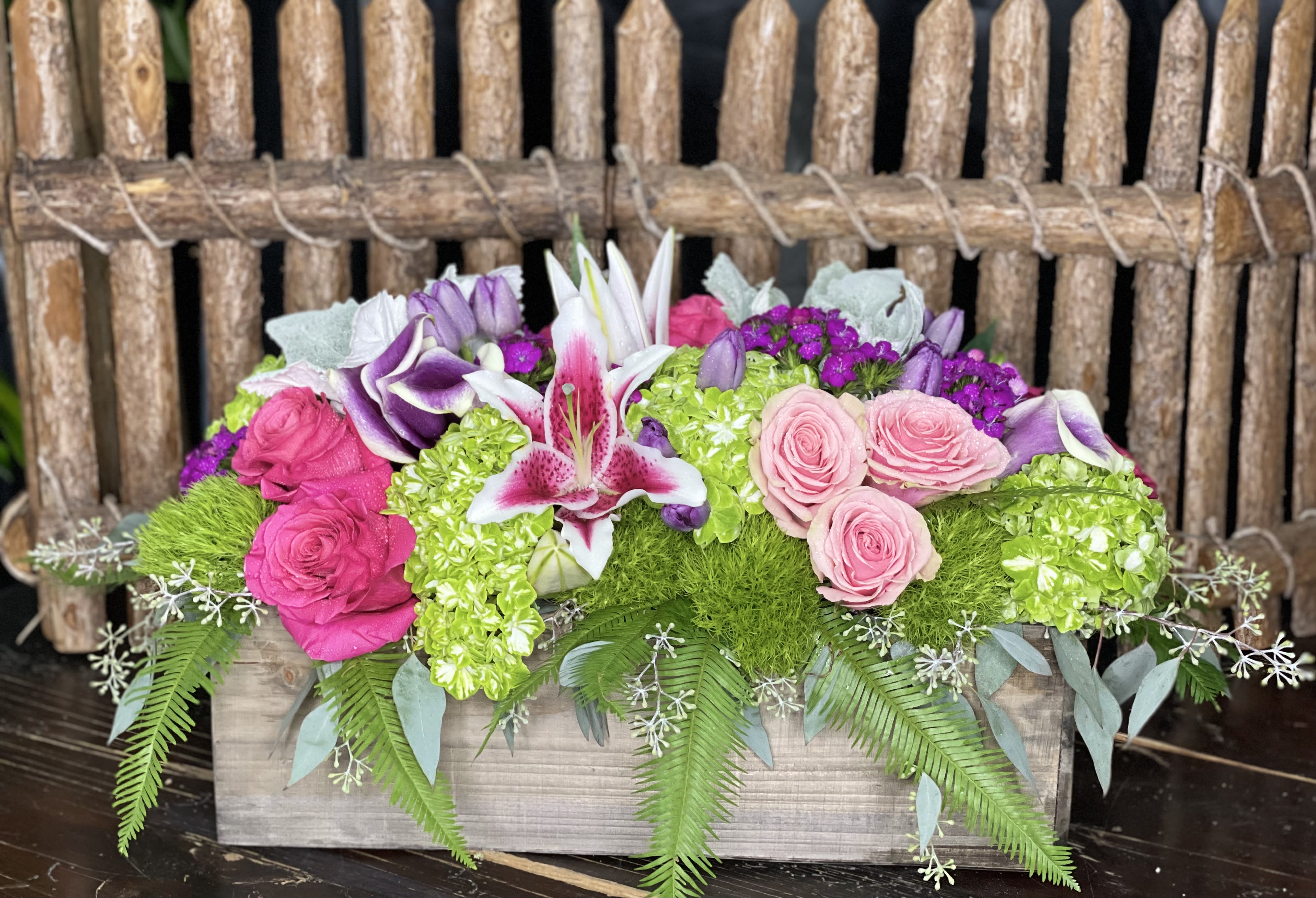 Pink and purple floral arrangement in a wooden box