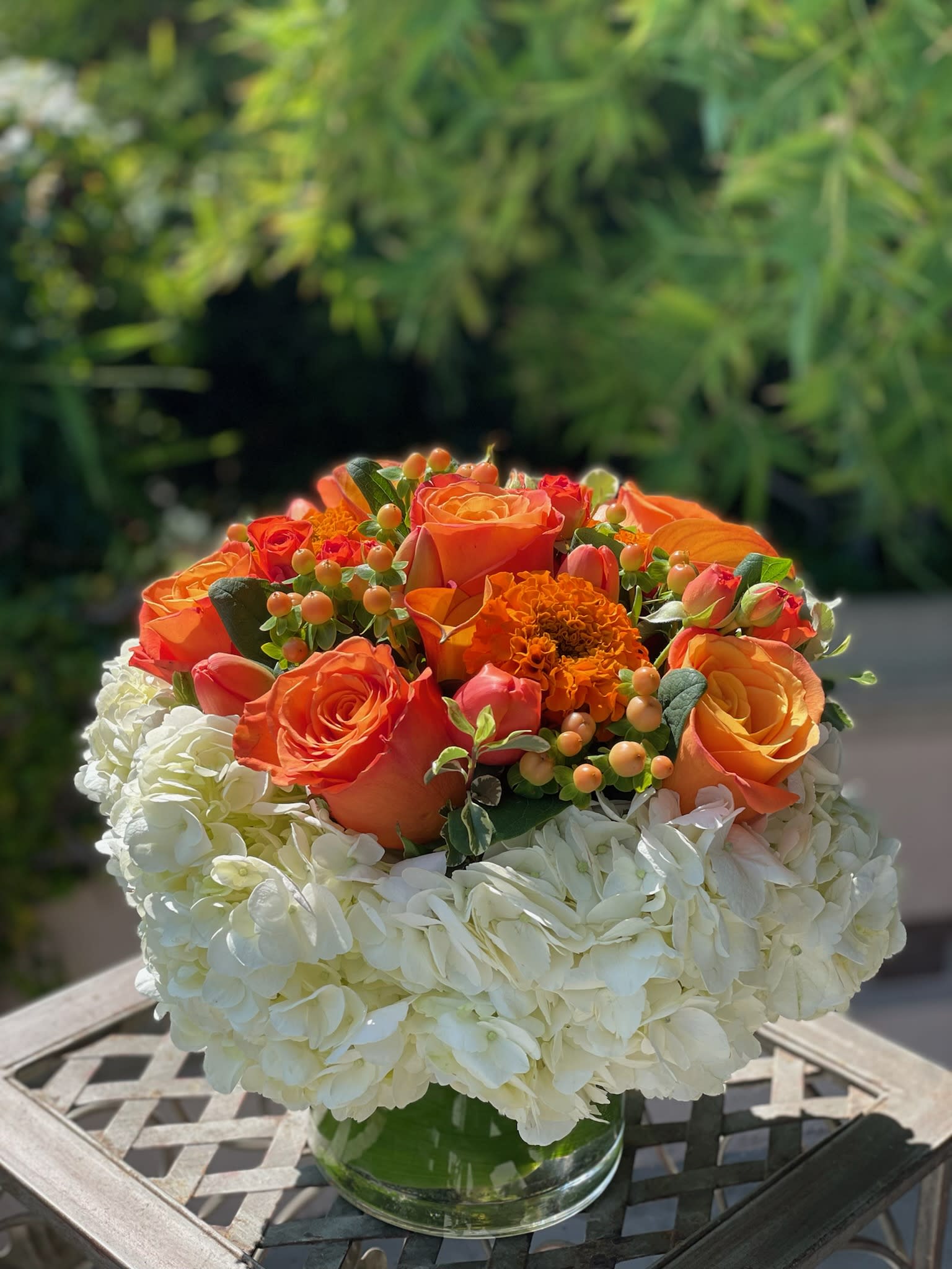 Orange roses and white hydrangeas in a clear glass vase