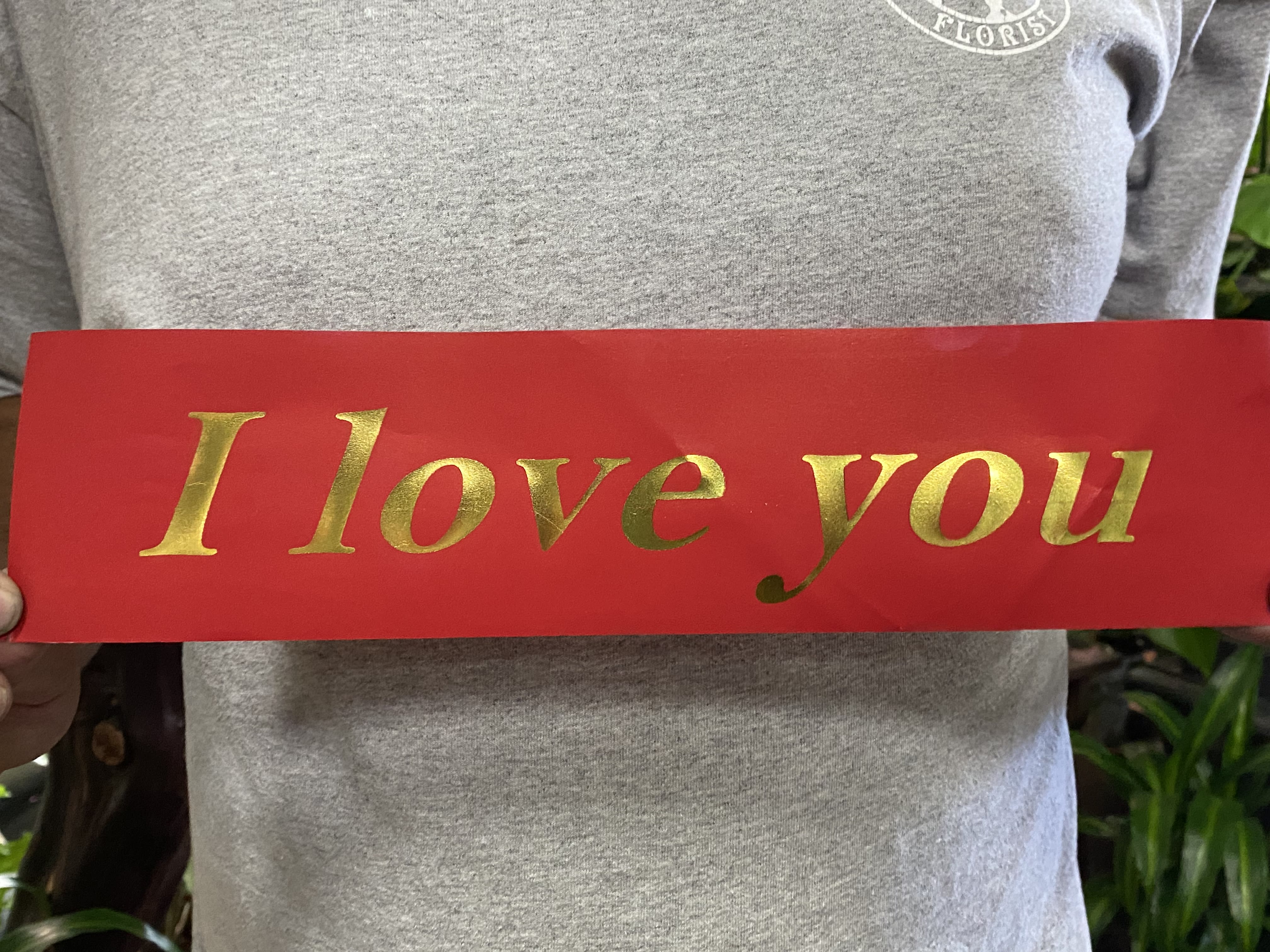 Person holding a red sign that says "I love you" in gold letters