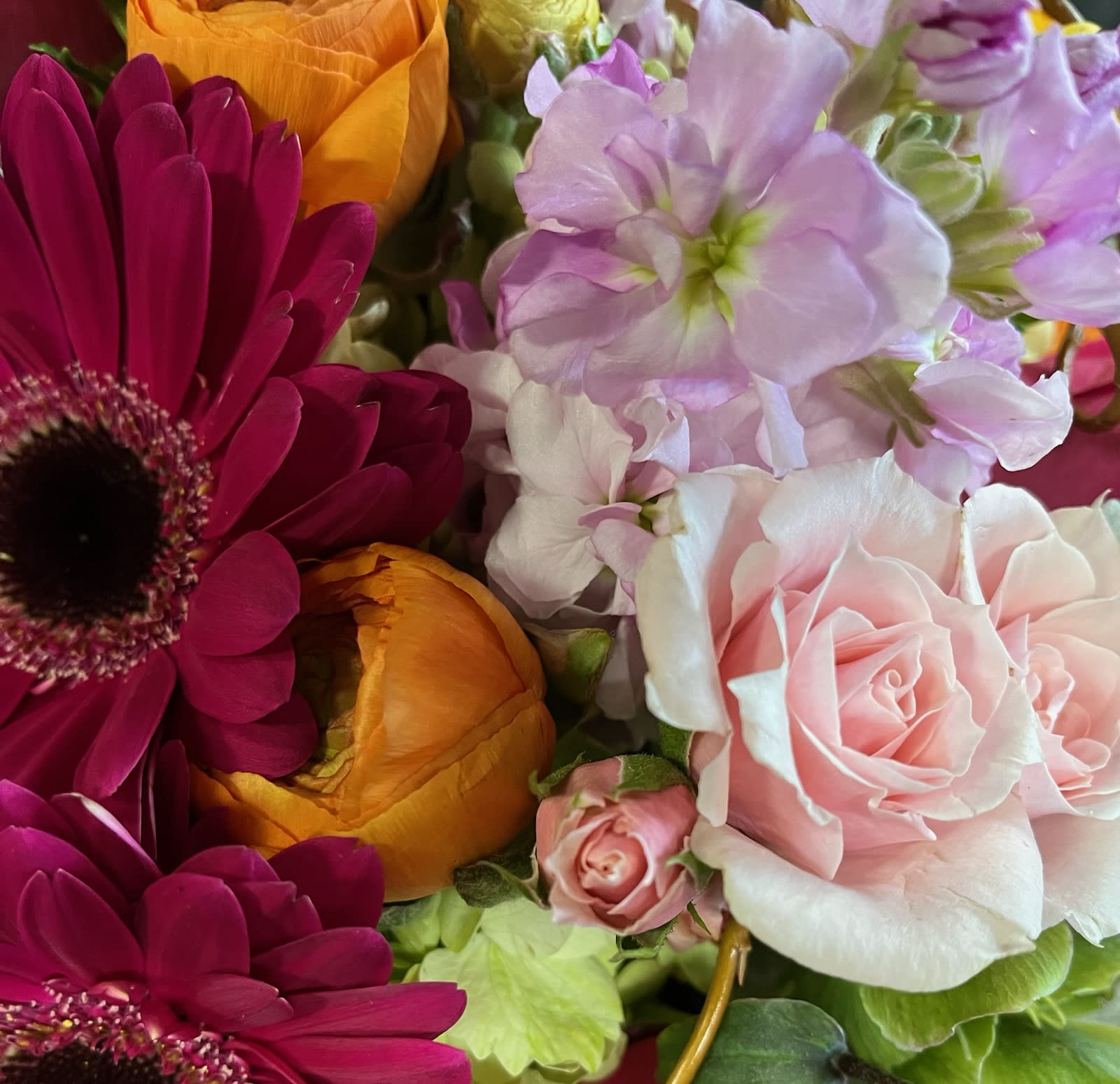 Close-up bouquet of pink roses, magenta daisies, and orange blooms