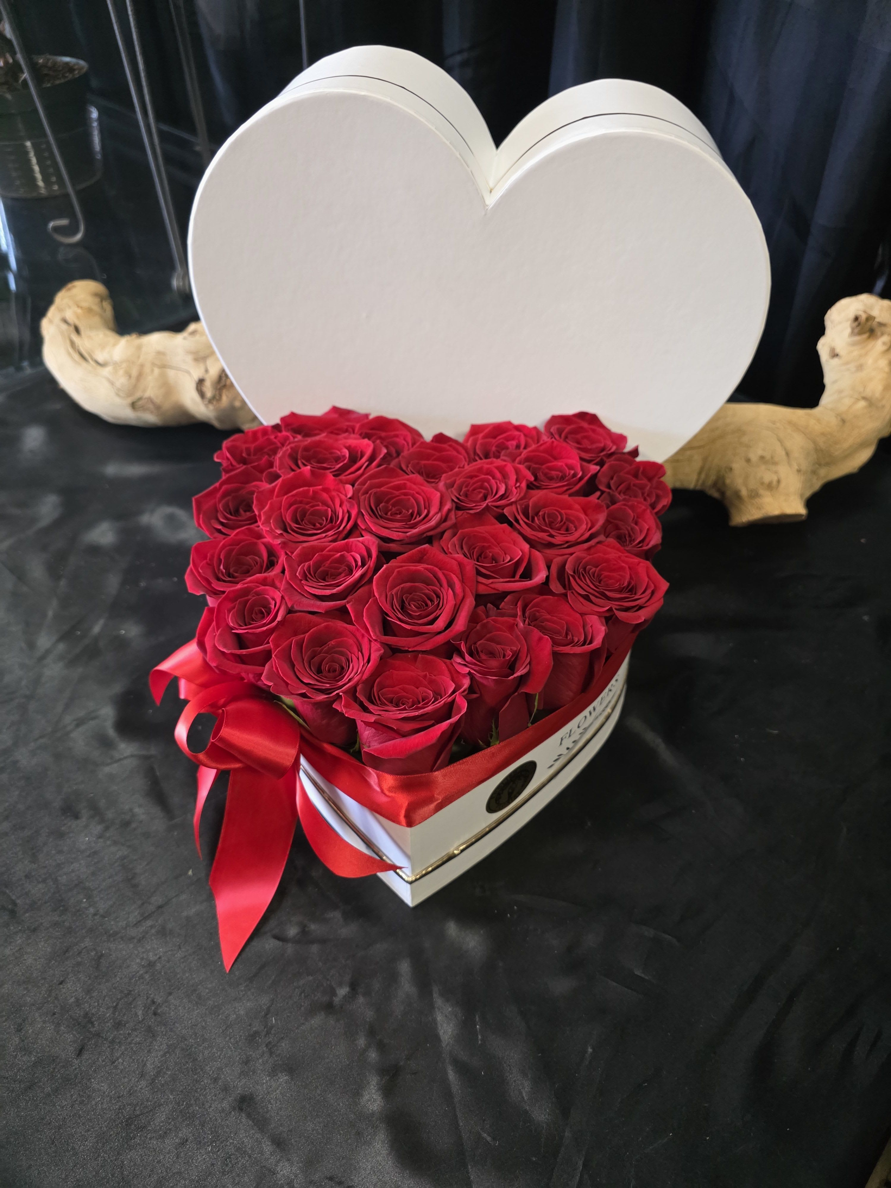 Heart-shaped box filled with red roses and a red ribbon