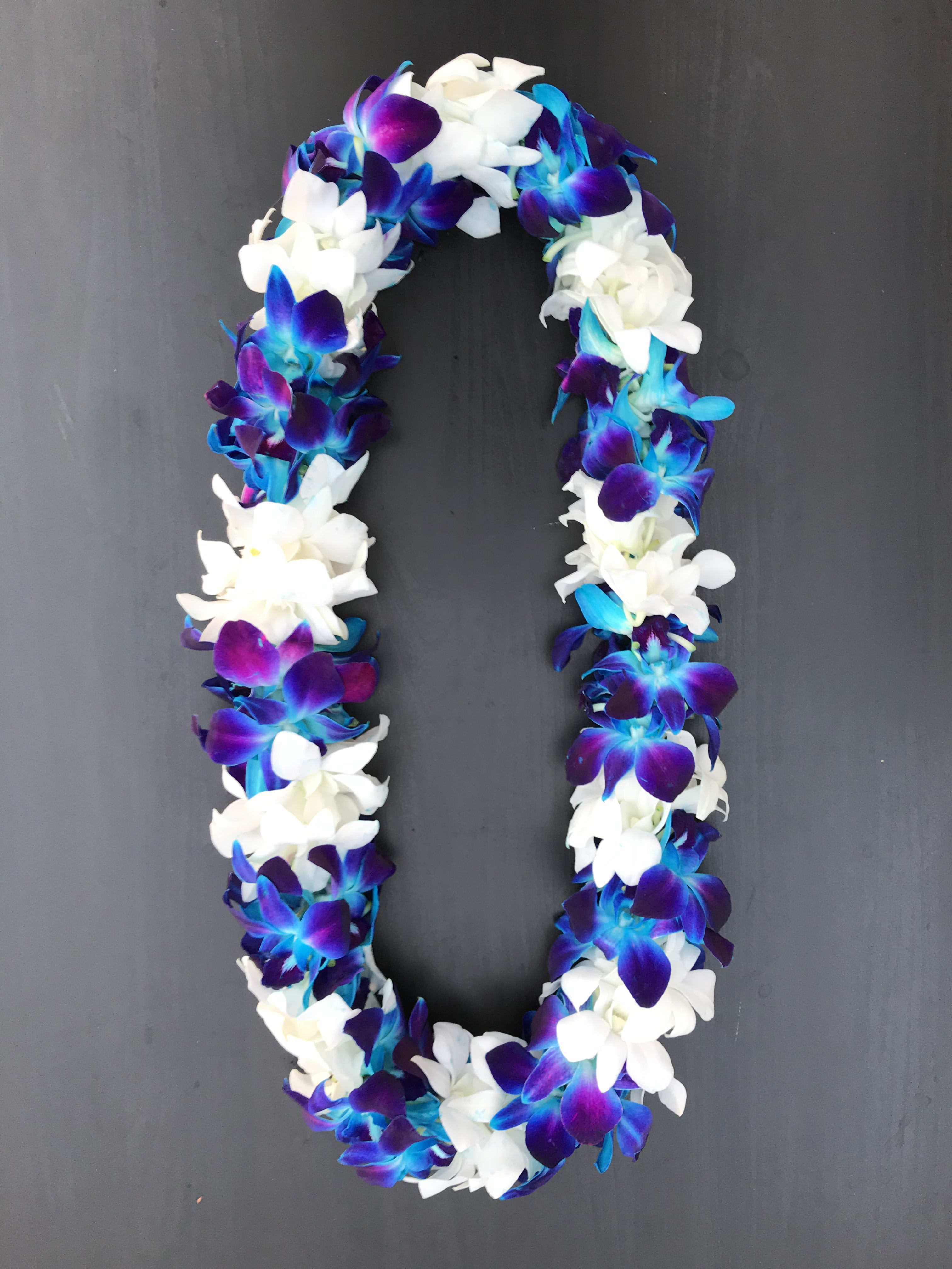 A purple, blue, and white flower lei on a dark background