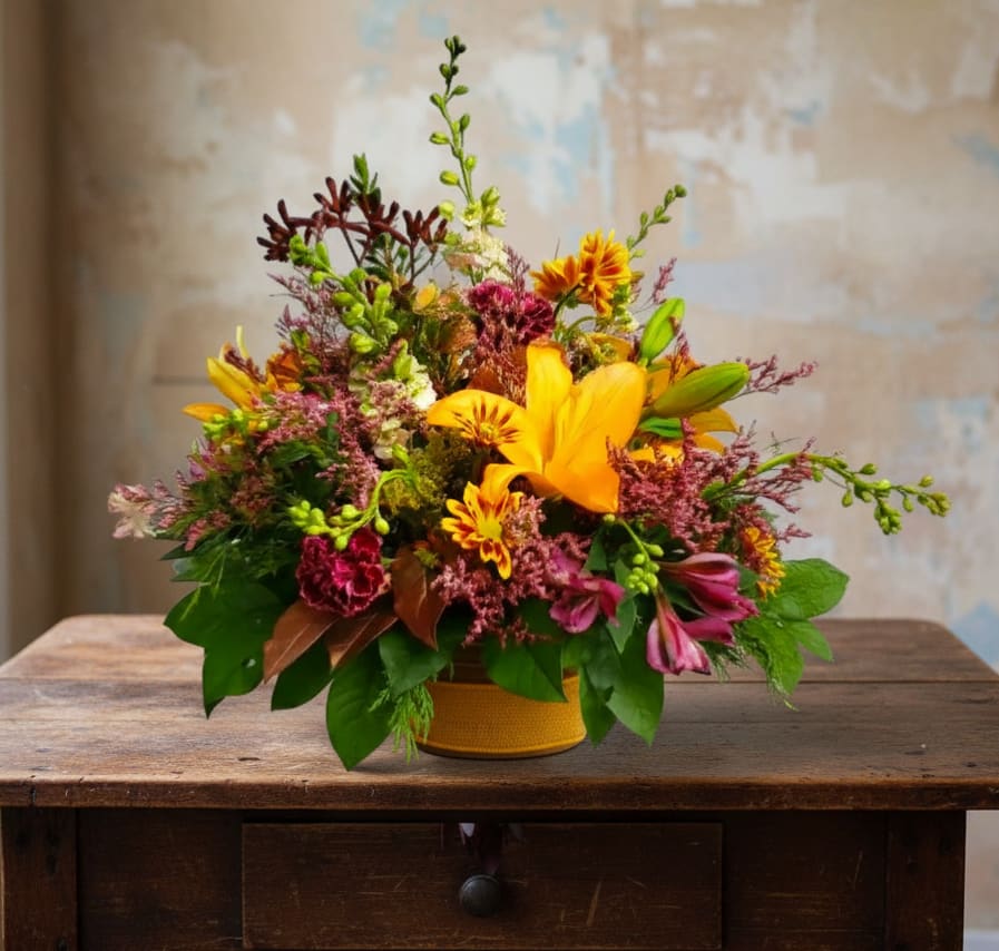 Bright mixed bouquet in a yellow container with orange lilies and pink blooms
