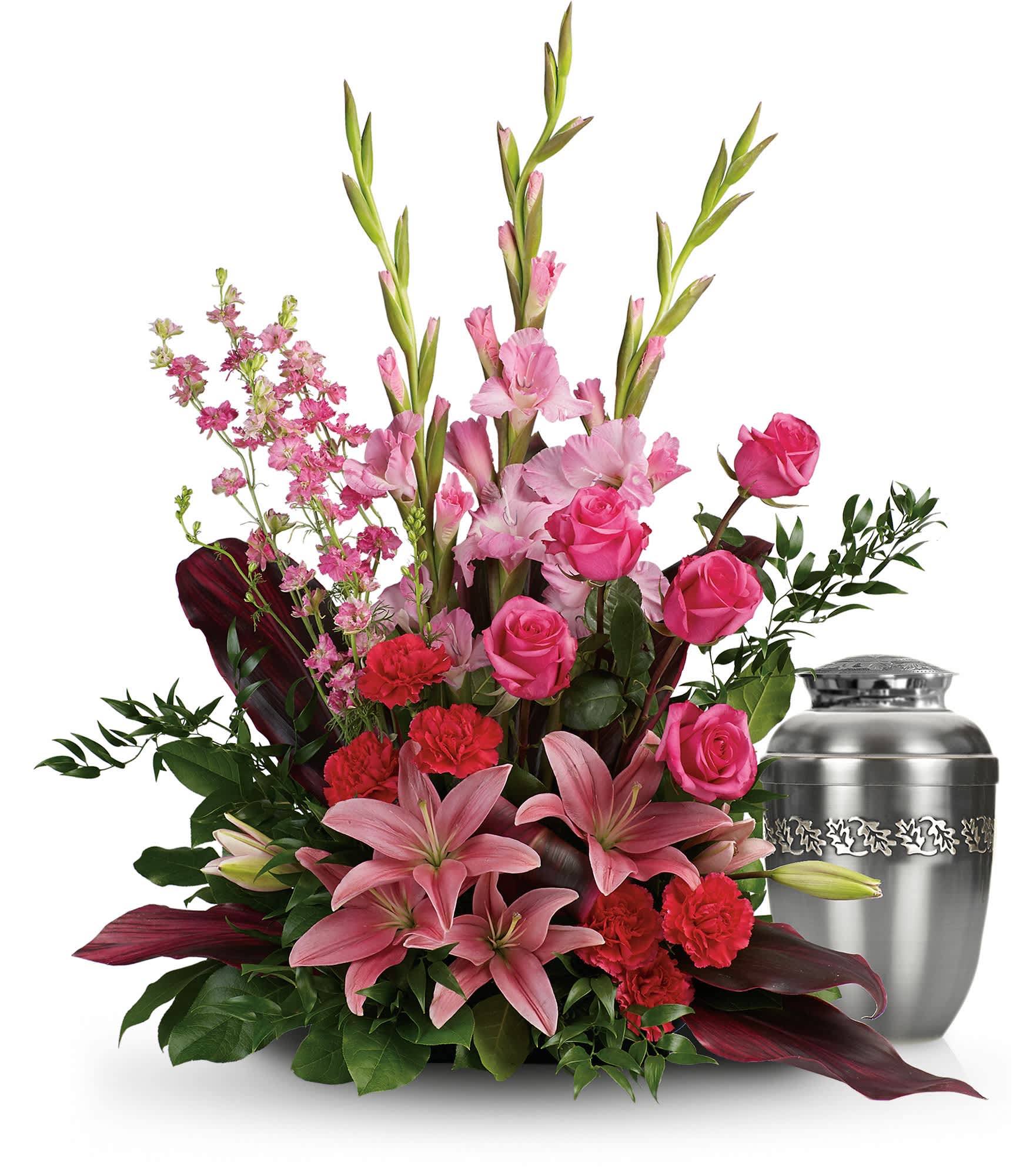Pink lilies, roses, and carnations arranged beside a silver urn
