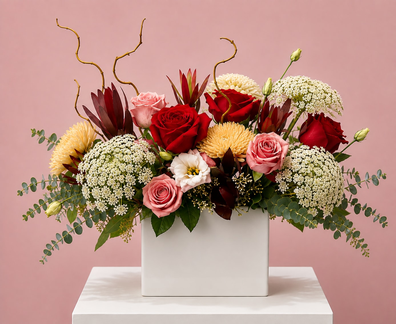 Mixed bouquet of red and pink roses in a white rectangular vase