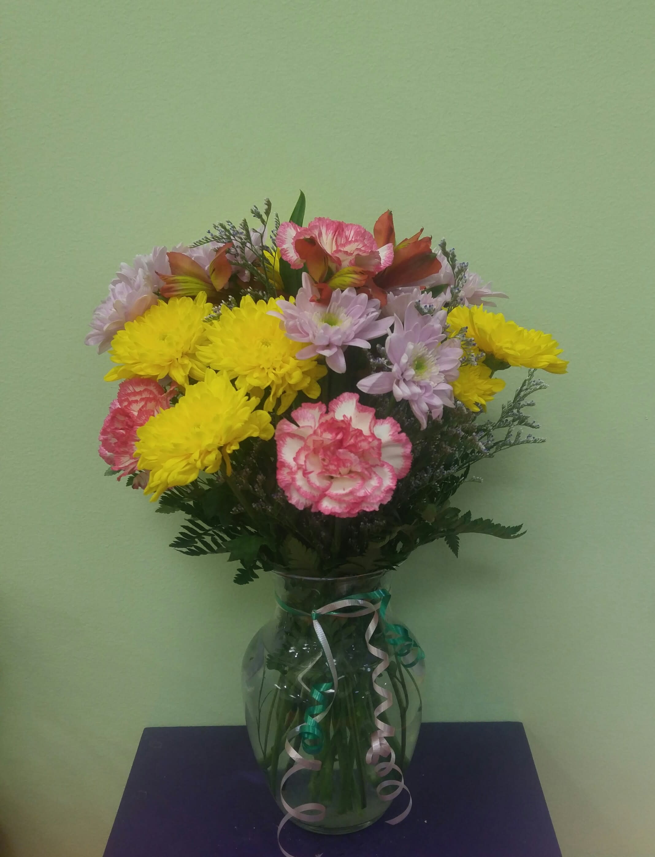 Bouquet of yellow chrysanthemums and pink carnations in a glass vase