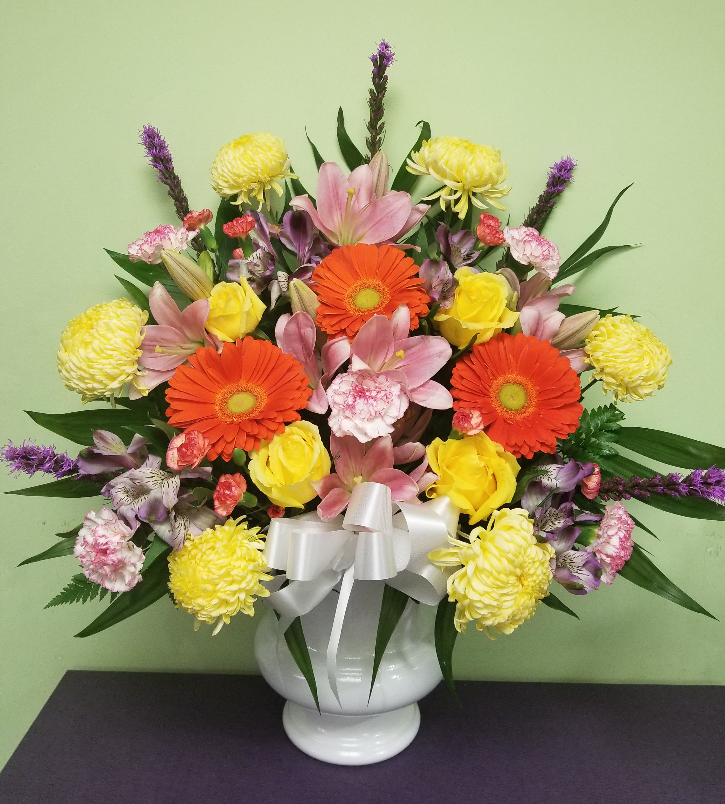 Colorful mixed bouquet in a white vase with a silver bow