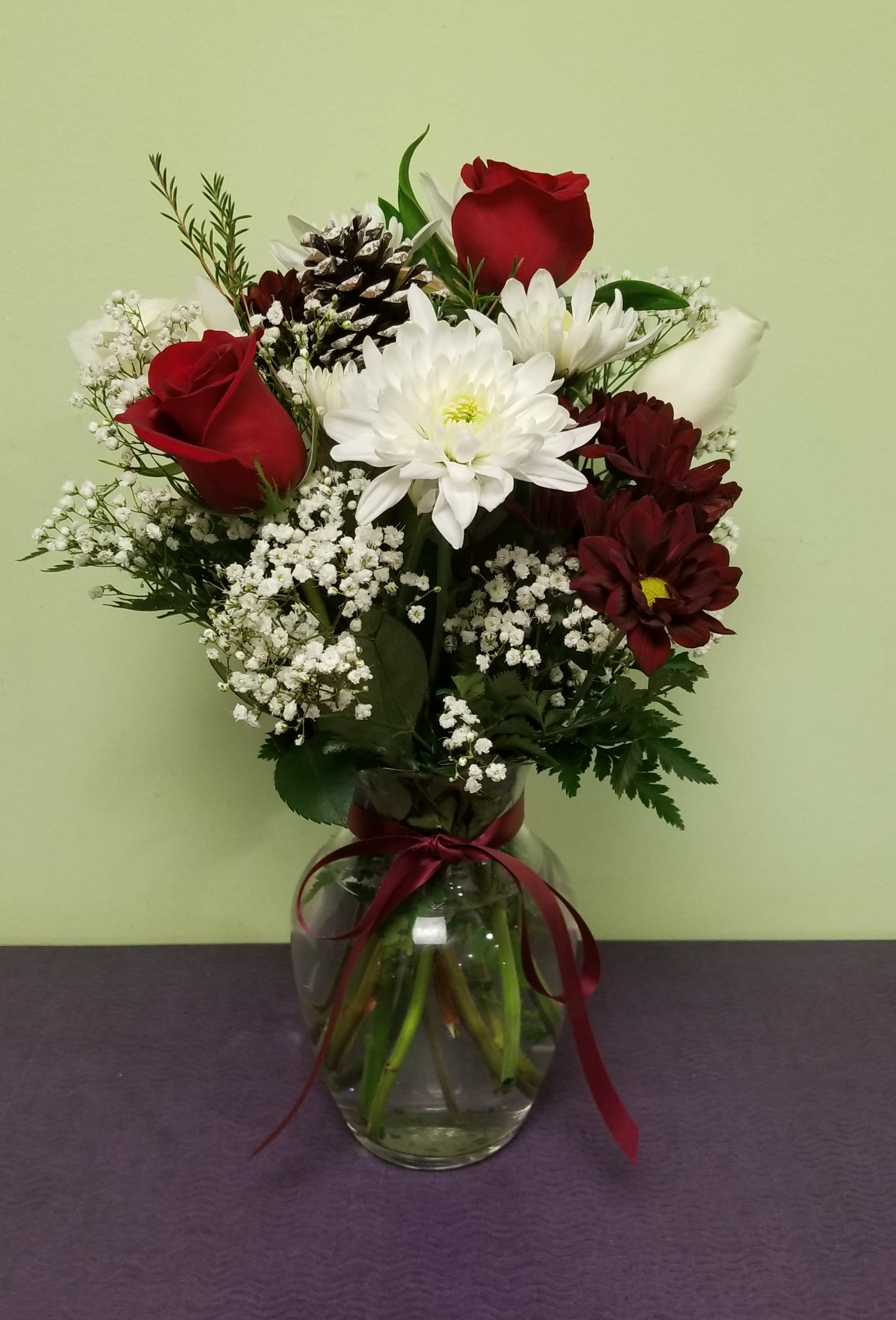 Bouquet of red roses, white chrysanthemums, and baby's breath in a glass vase