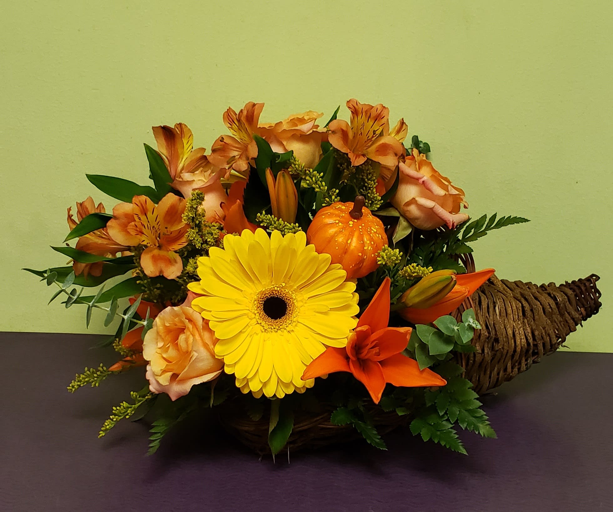Basket arrangement with yellow gerbera, orange lilies, and peach roses