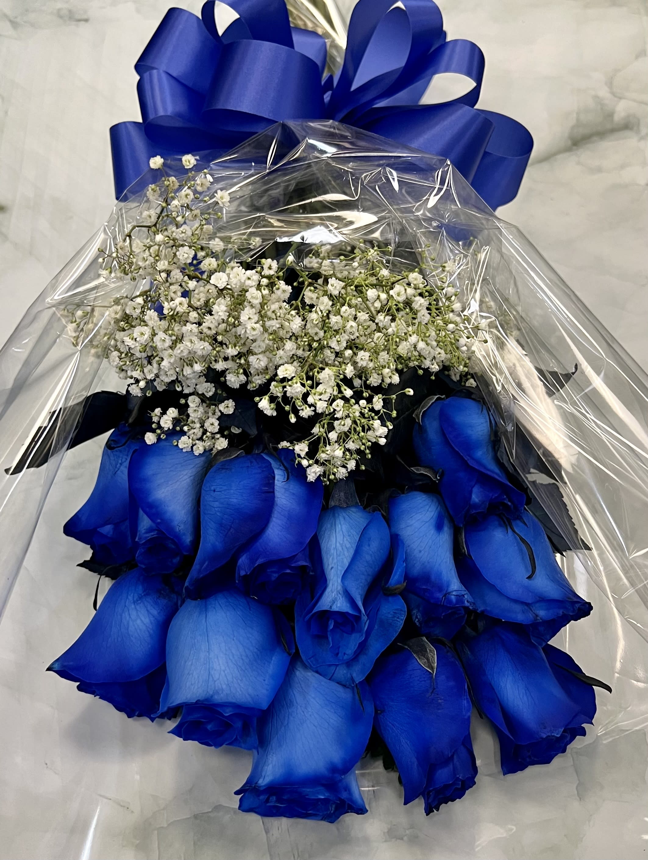 Bouquet of blue roses with white baby's breath wrapped in clear plastic