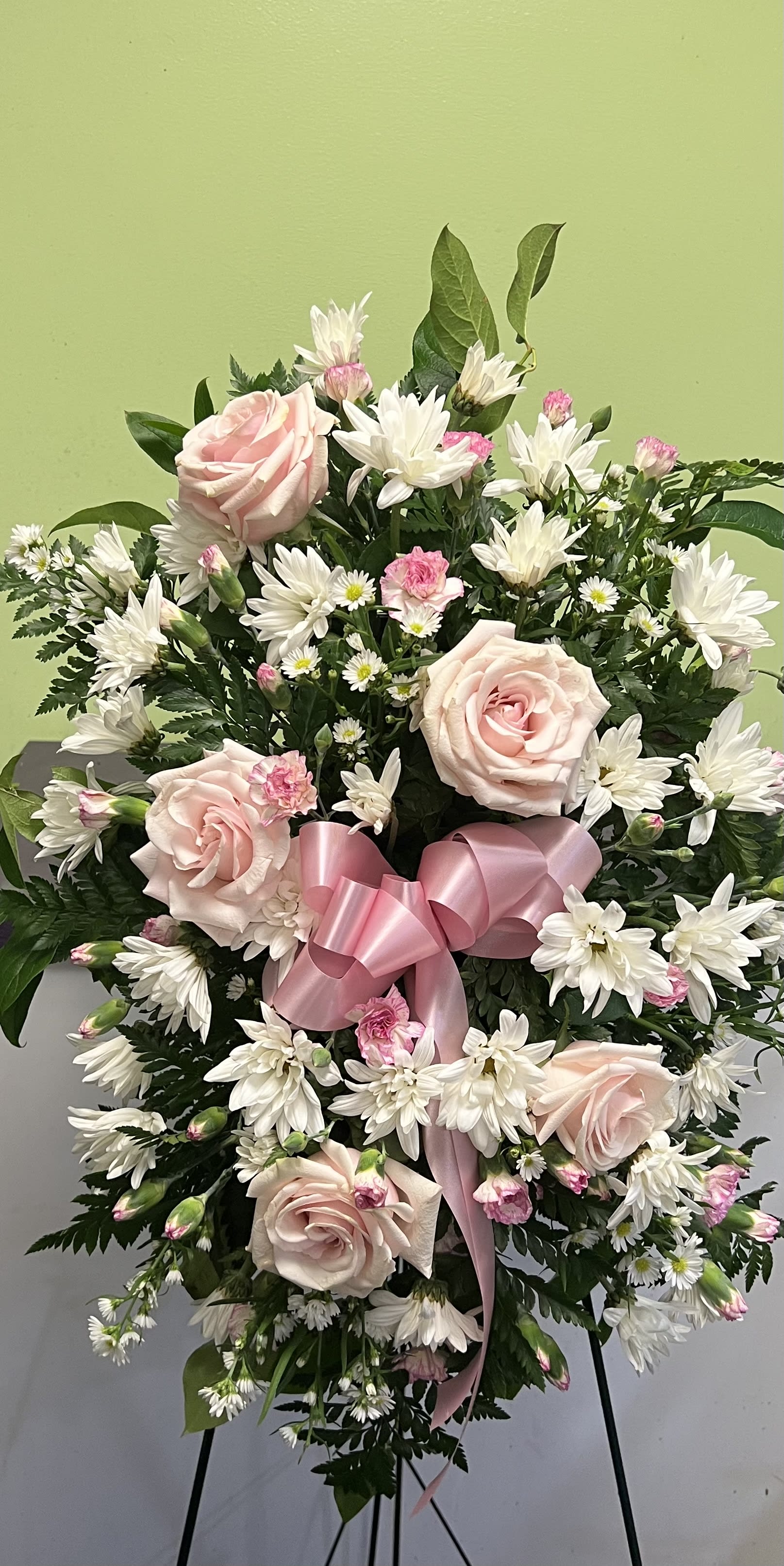 Pink roses and white daisies in a standing spray with a pink ribbon