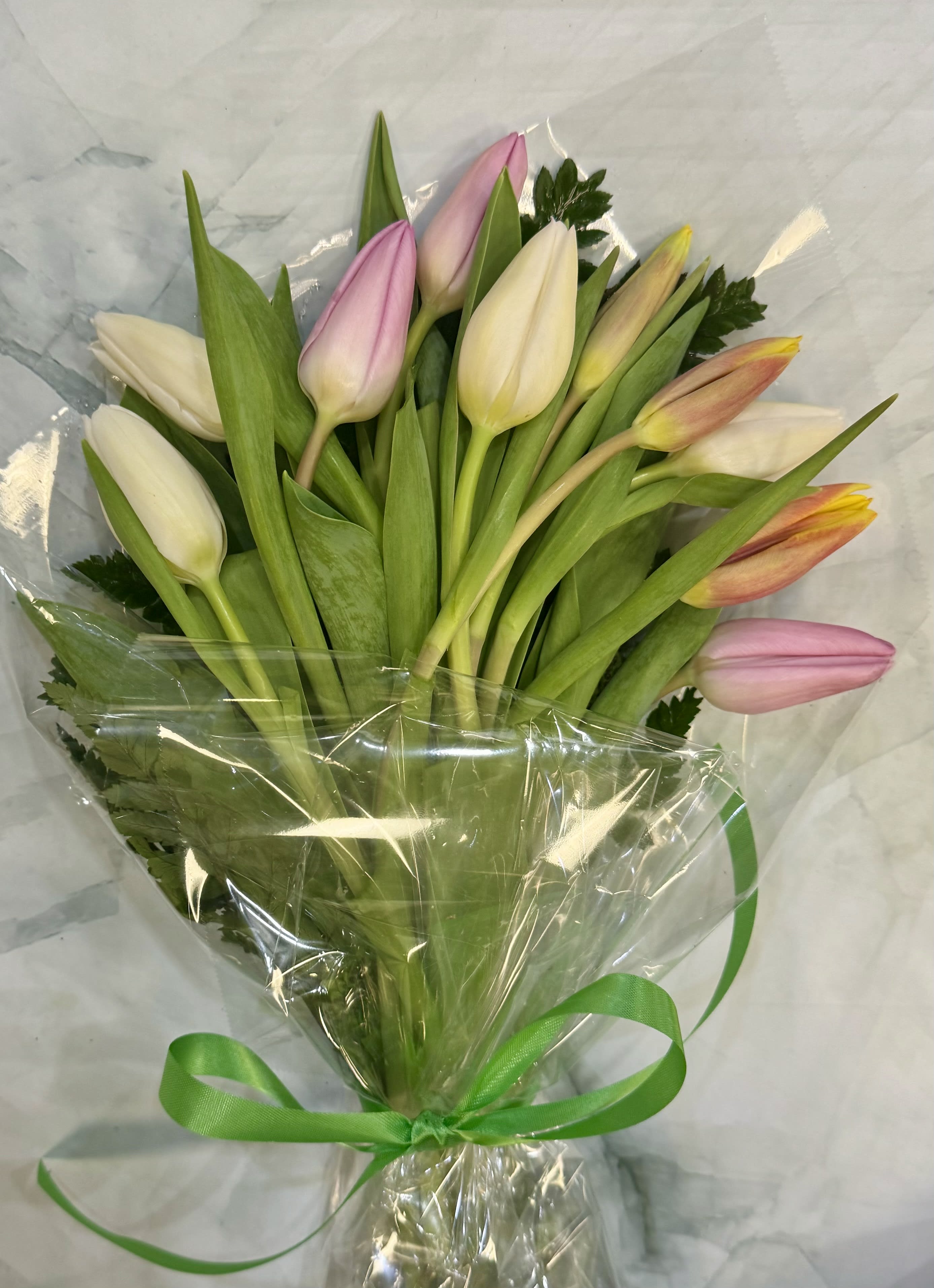 Bouquet of pink, white, and yellow tulips wrapped in clear plastic