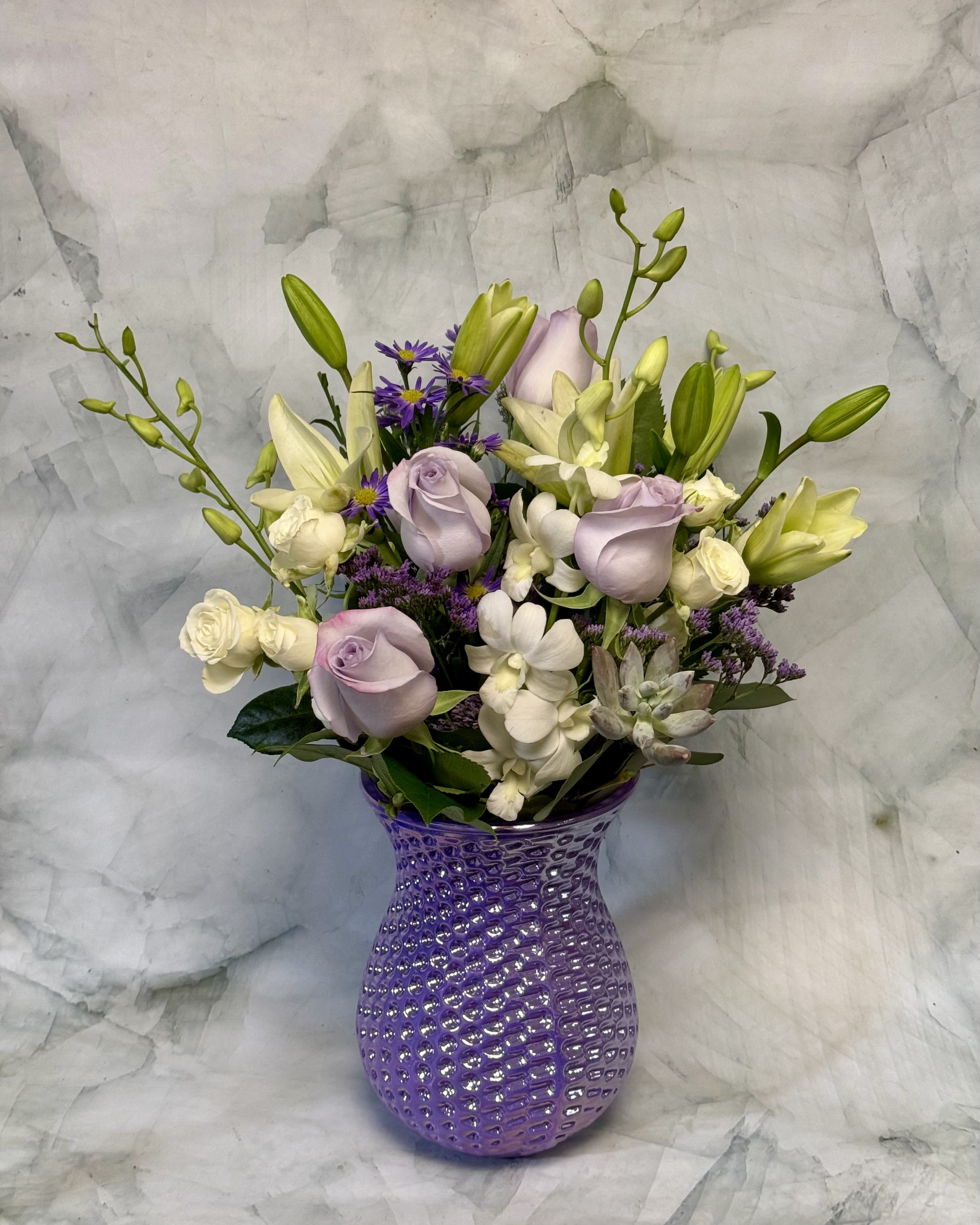 Lavender roses and white lilies in a purple textured vase