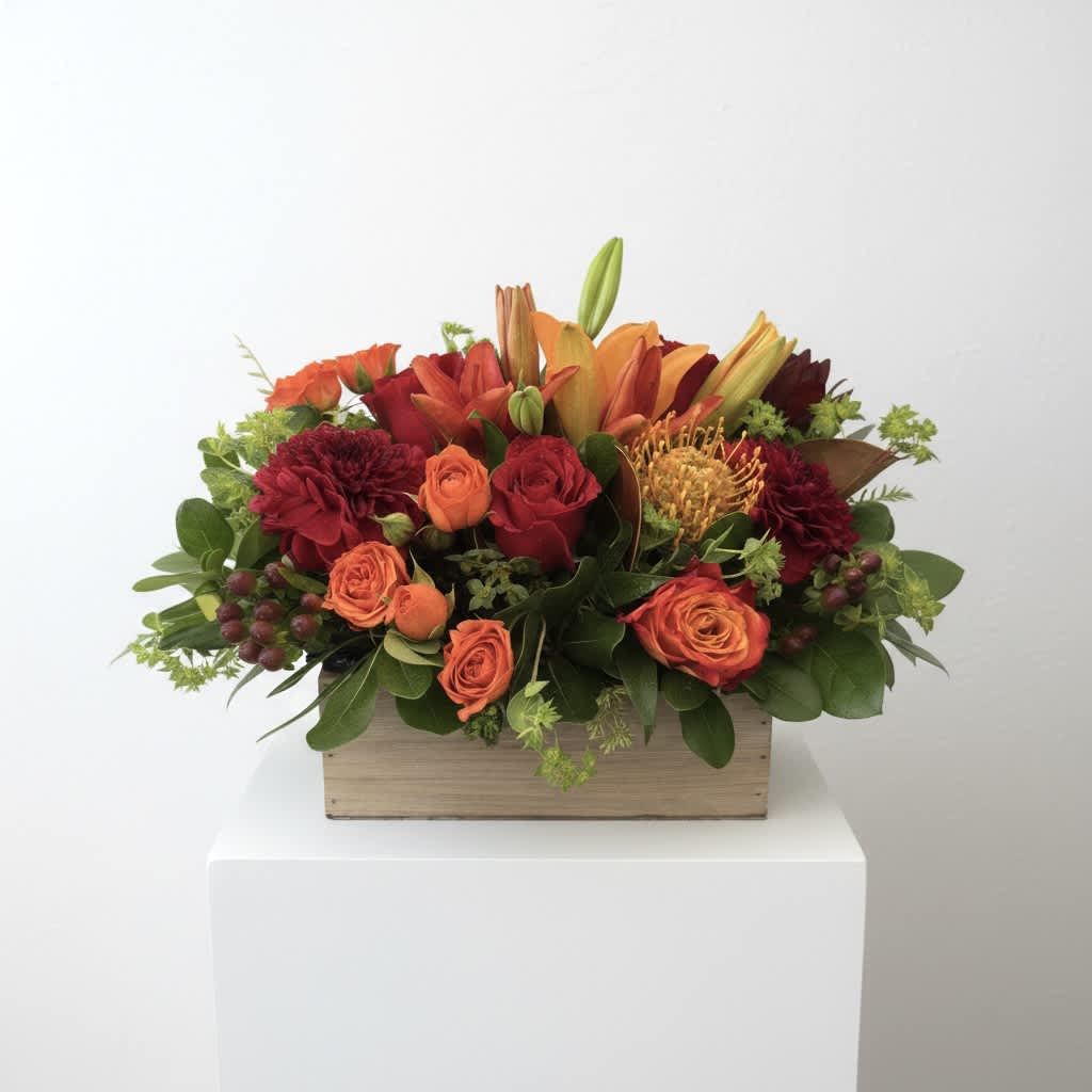 Orange and red floral arrangement in a wooden box