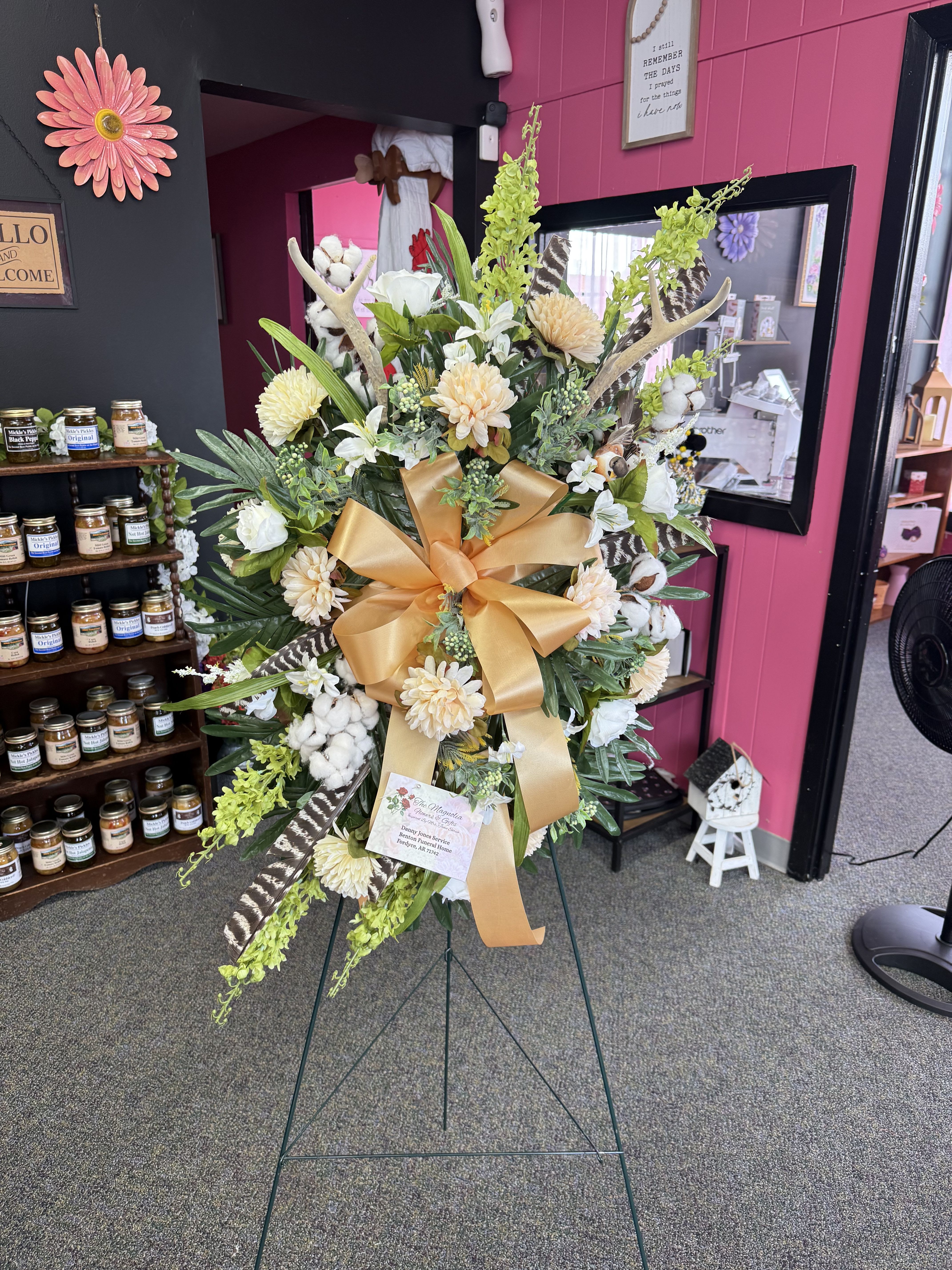 Tall standing floral spray with white and cream blooms and a gold ribbon