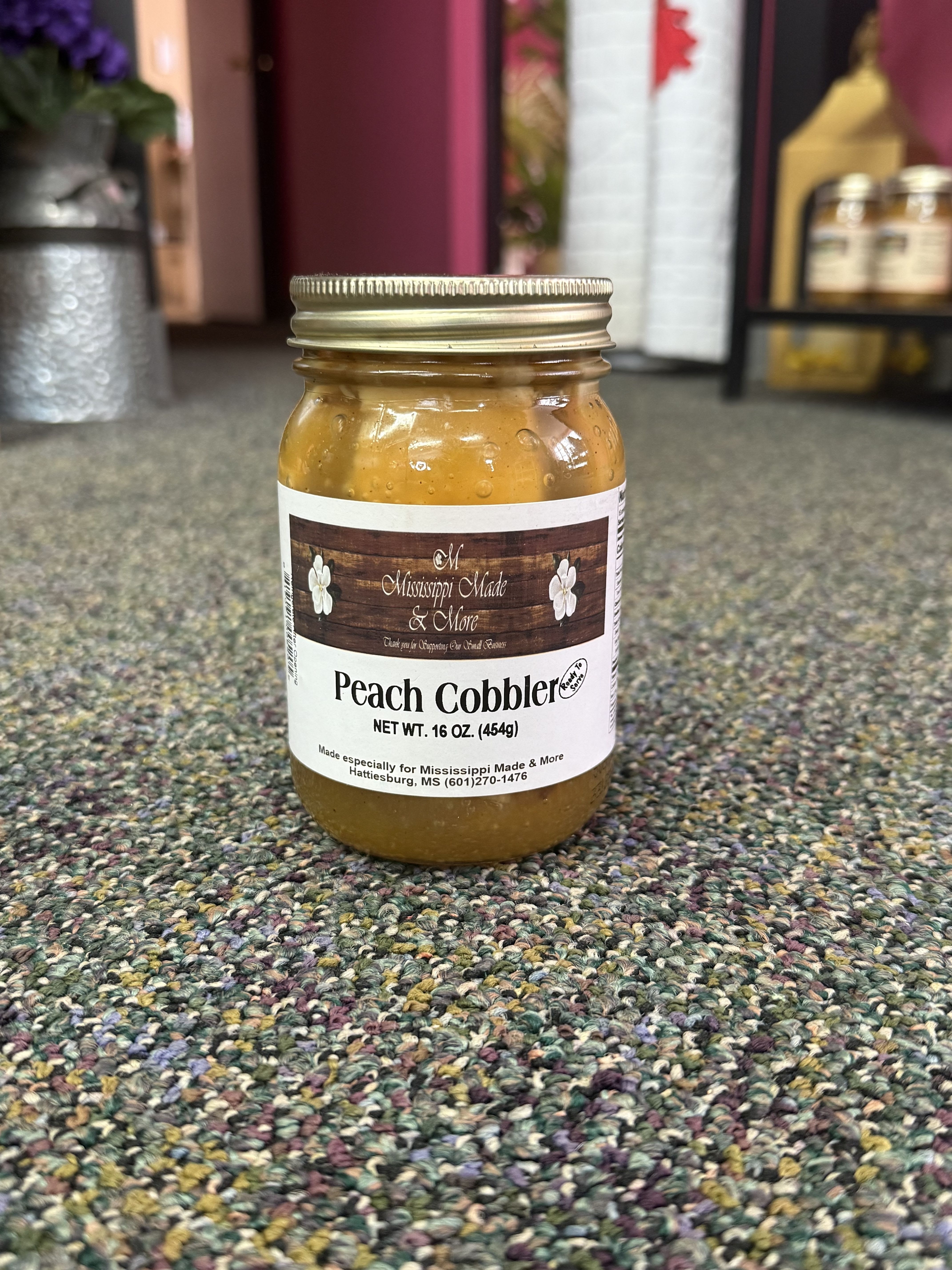 Jar of peach cobbler filling with a labeled metal lid
