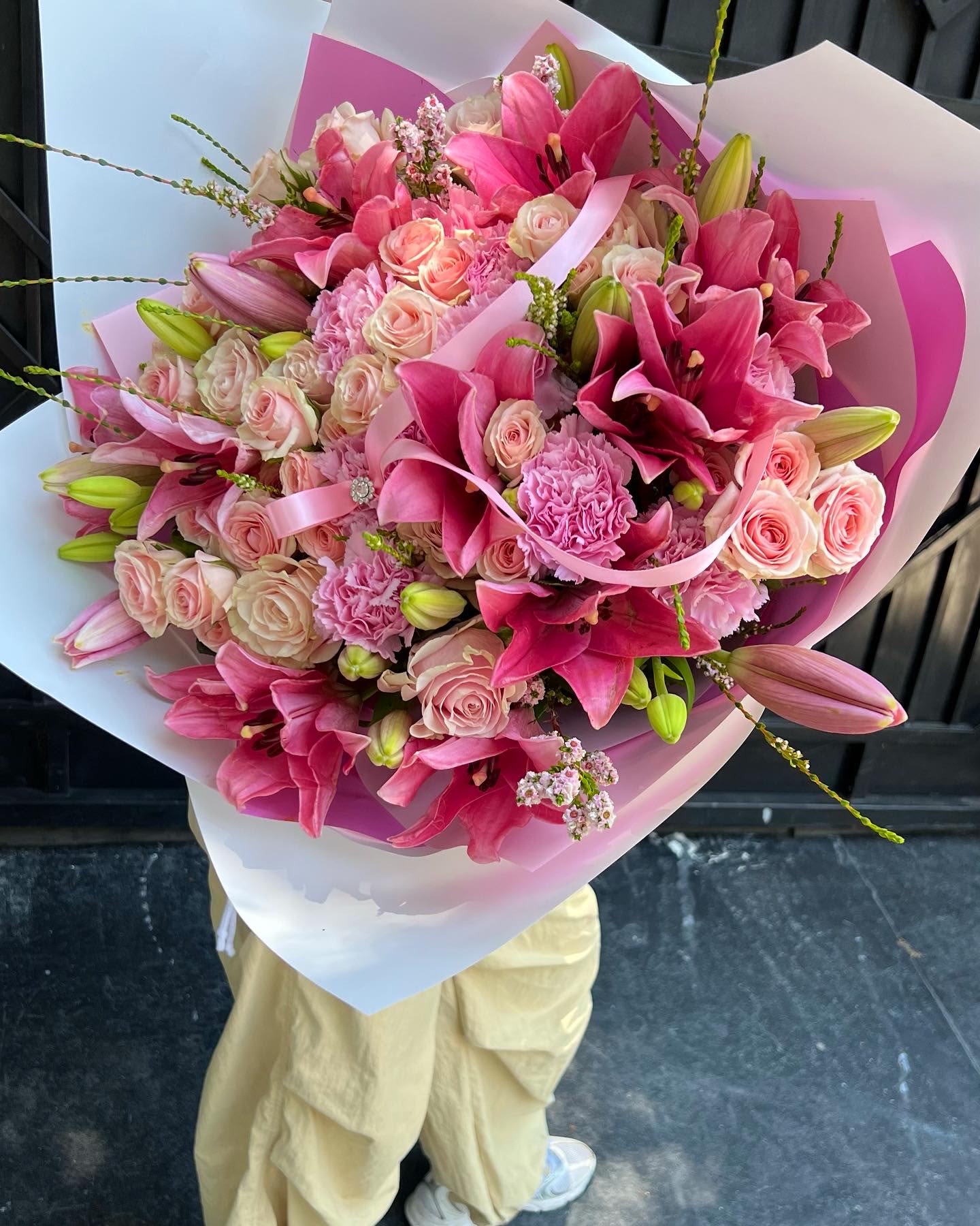 Pink bouquet with roses, lilies, and carnations wrapped in white and pink paper