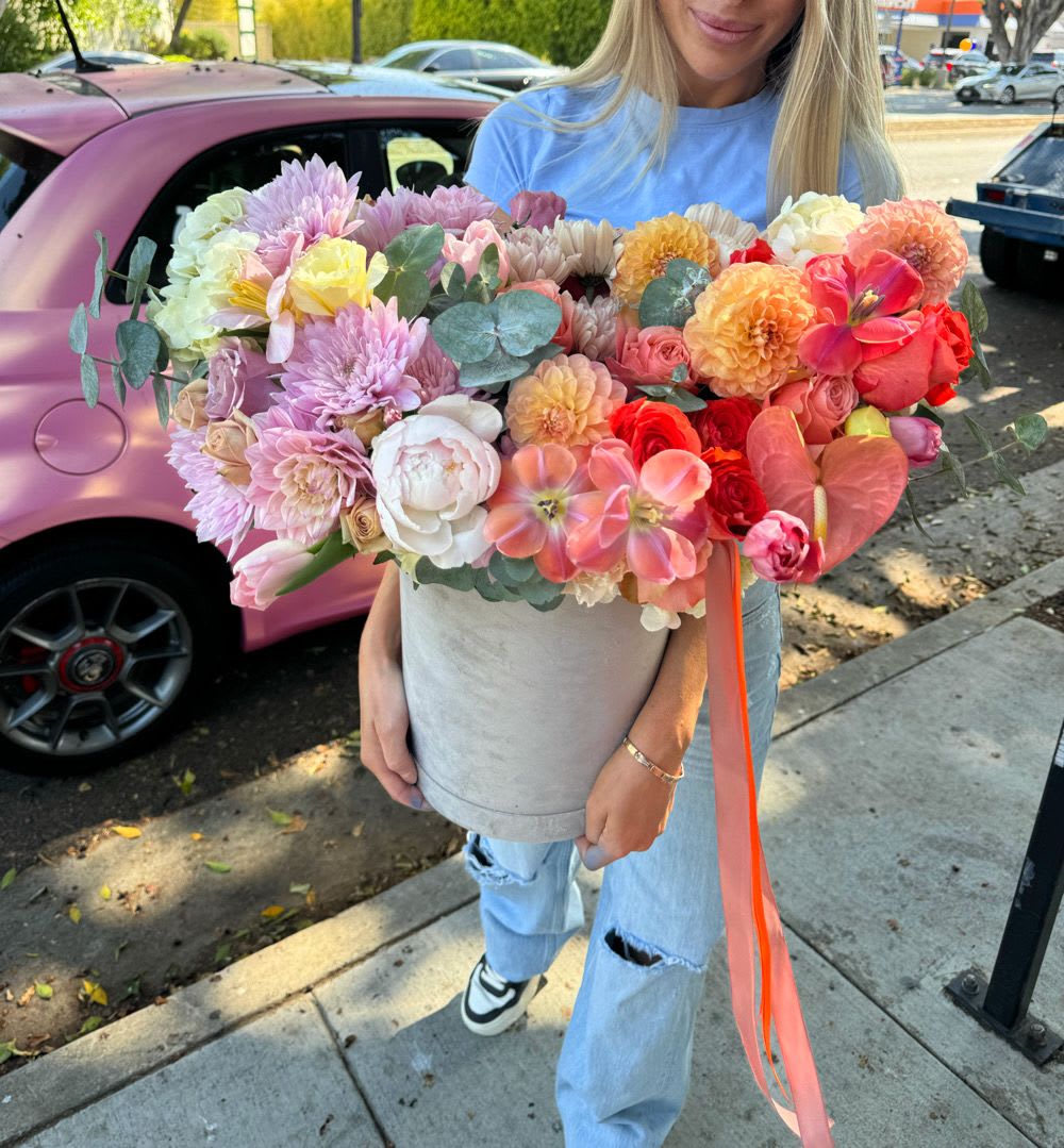 Large mixed bouquet in a gray hatbox held by a woman