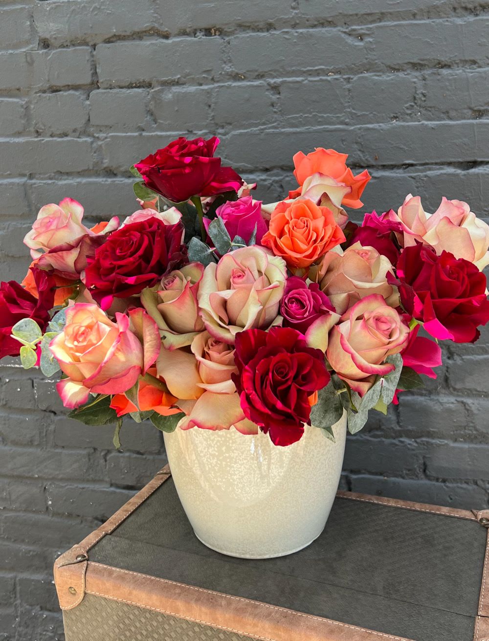 Bouquet of red, pink, and peach roses in a white vase