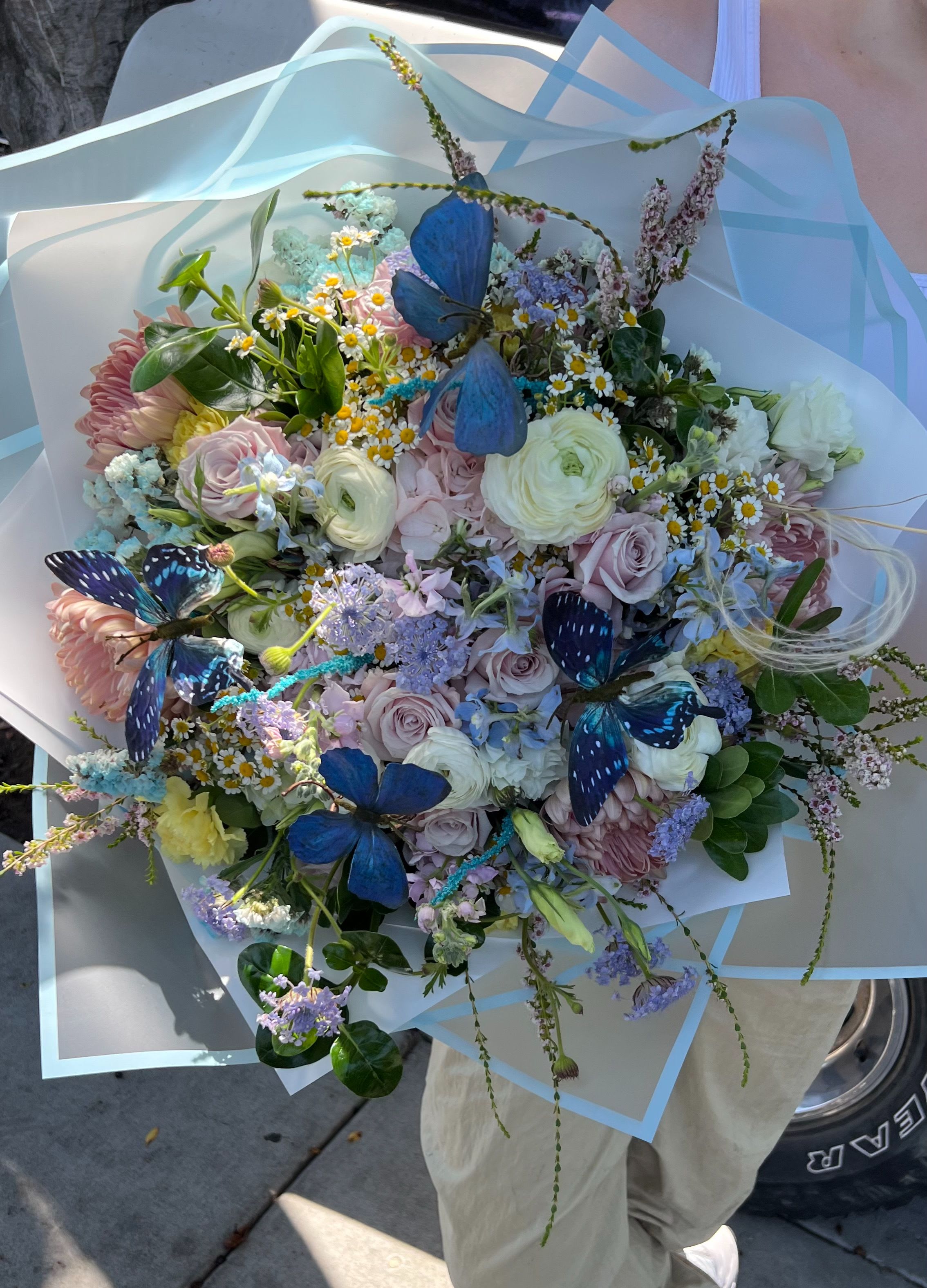 Large pastel bouquet with butterflies and mixed blooms wrapped in pale blue paper