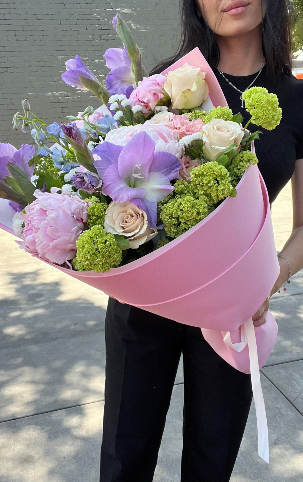 Large pastel bouquet with pink, purple, and cream flowers wrapped in pink paper