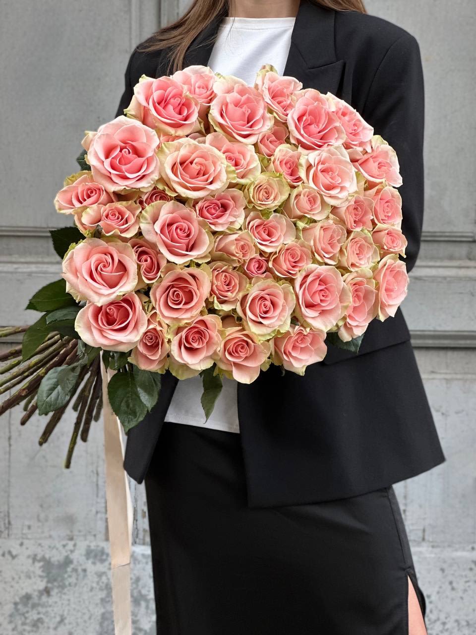 Large bouquet of pink roses held by a person in a black suit