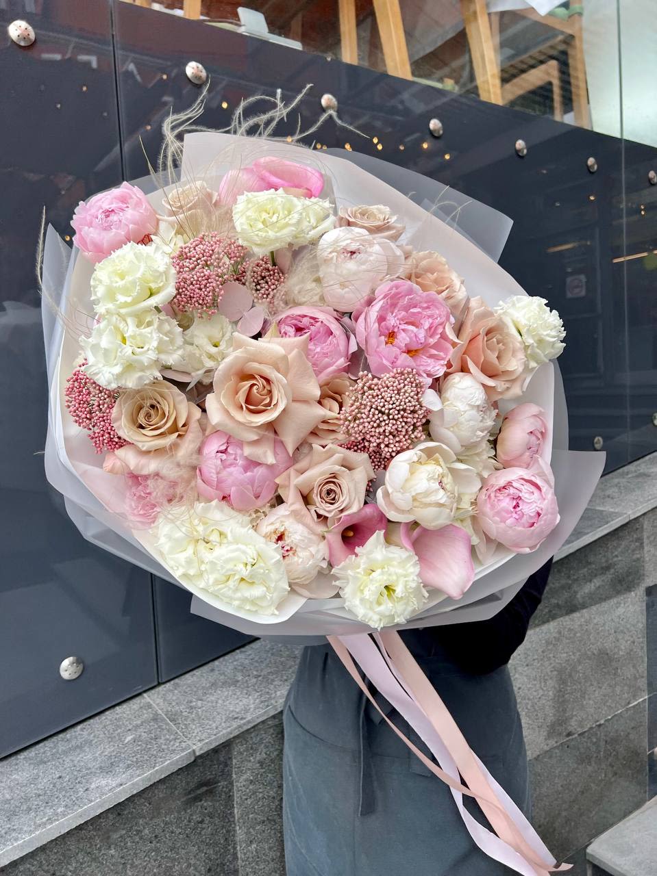 Large pastel bouquet of pink and cream flowers wrapped in translucent paper