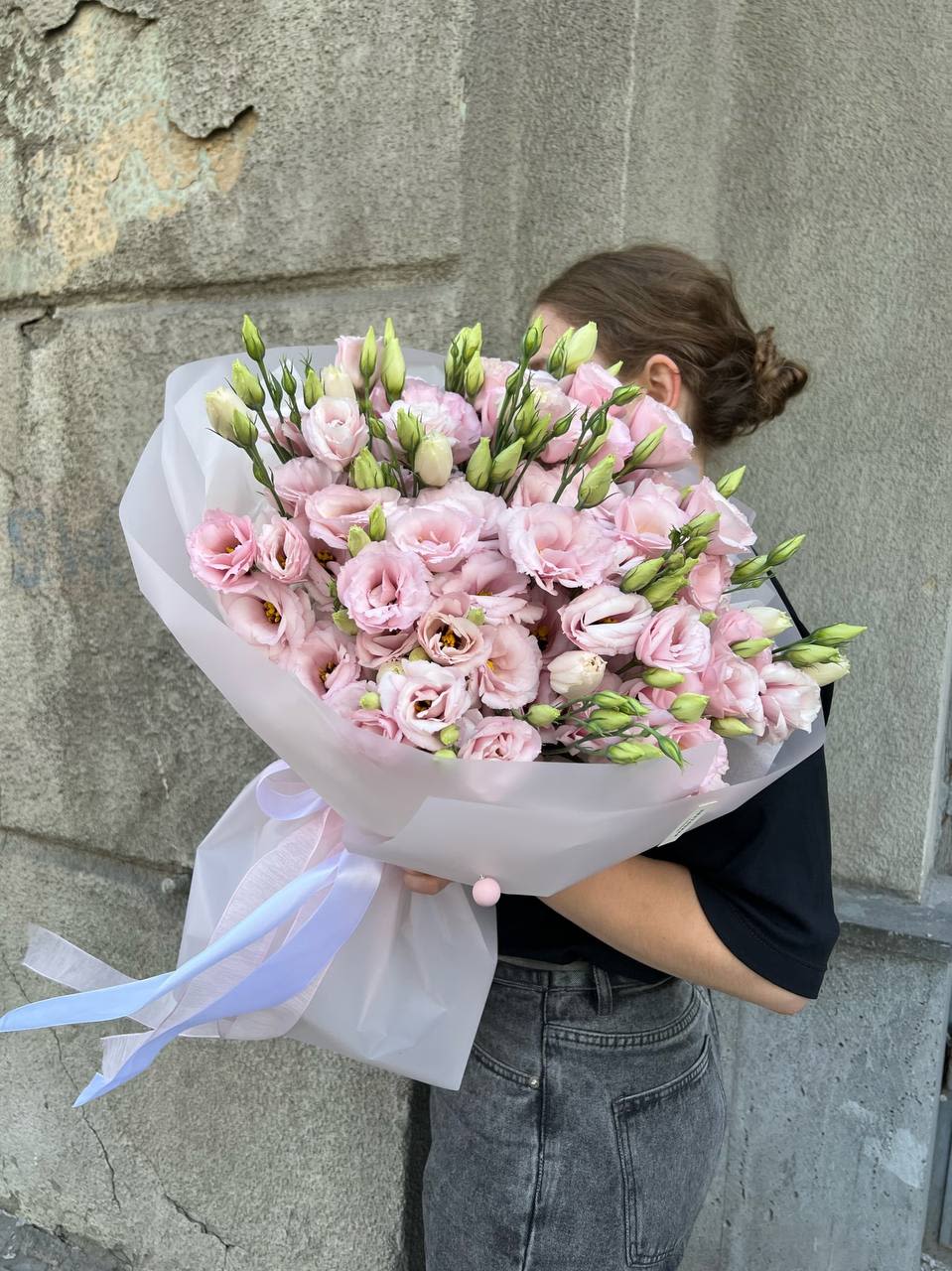 Large bouquet of pale pink lisianthus wrapped in white paper with ribbon